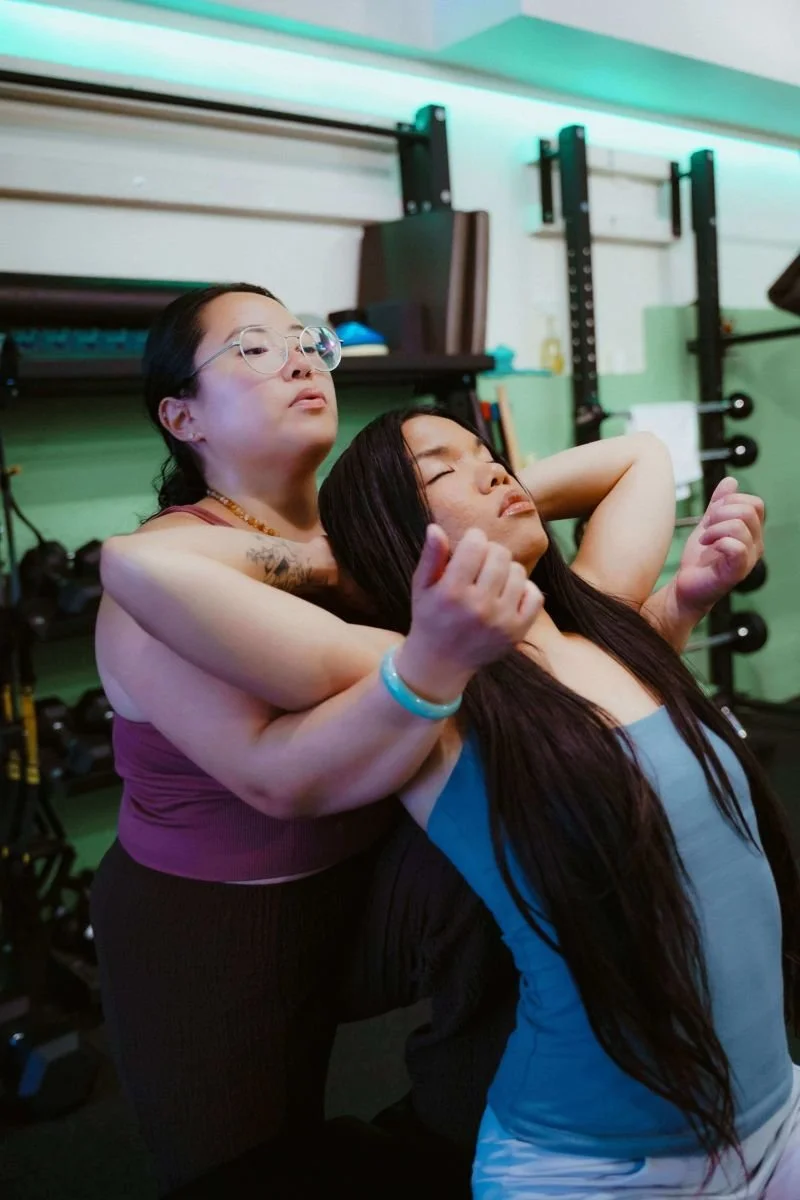 Lisa Paule guiding a client through an assisted upper-body stretch during a stretch therapy session.
