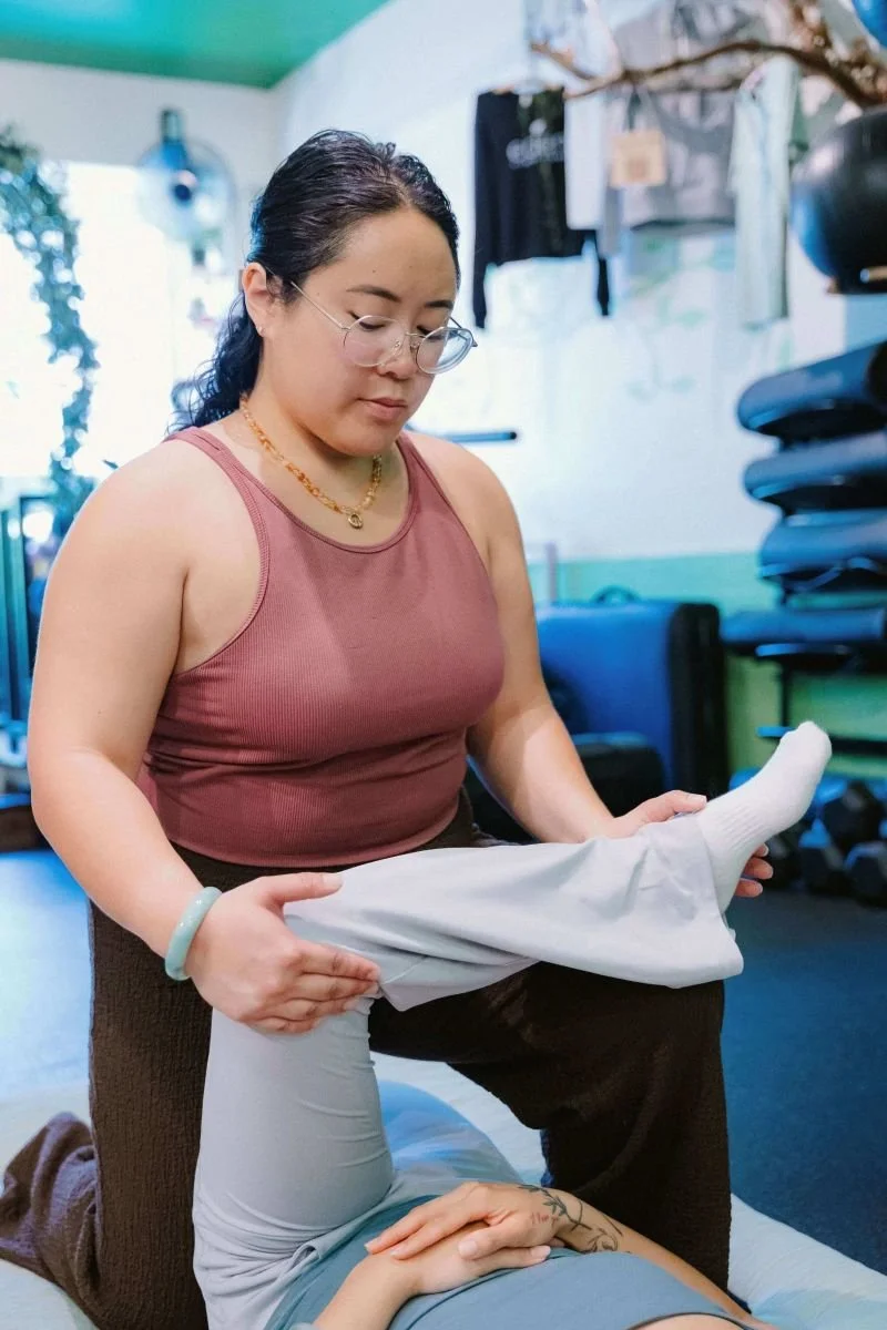 Lisa Paule providing one-on-one assisted stretching for a client's hip and leg mobility.