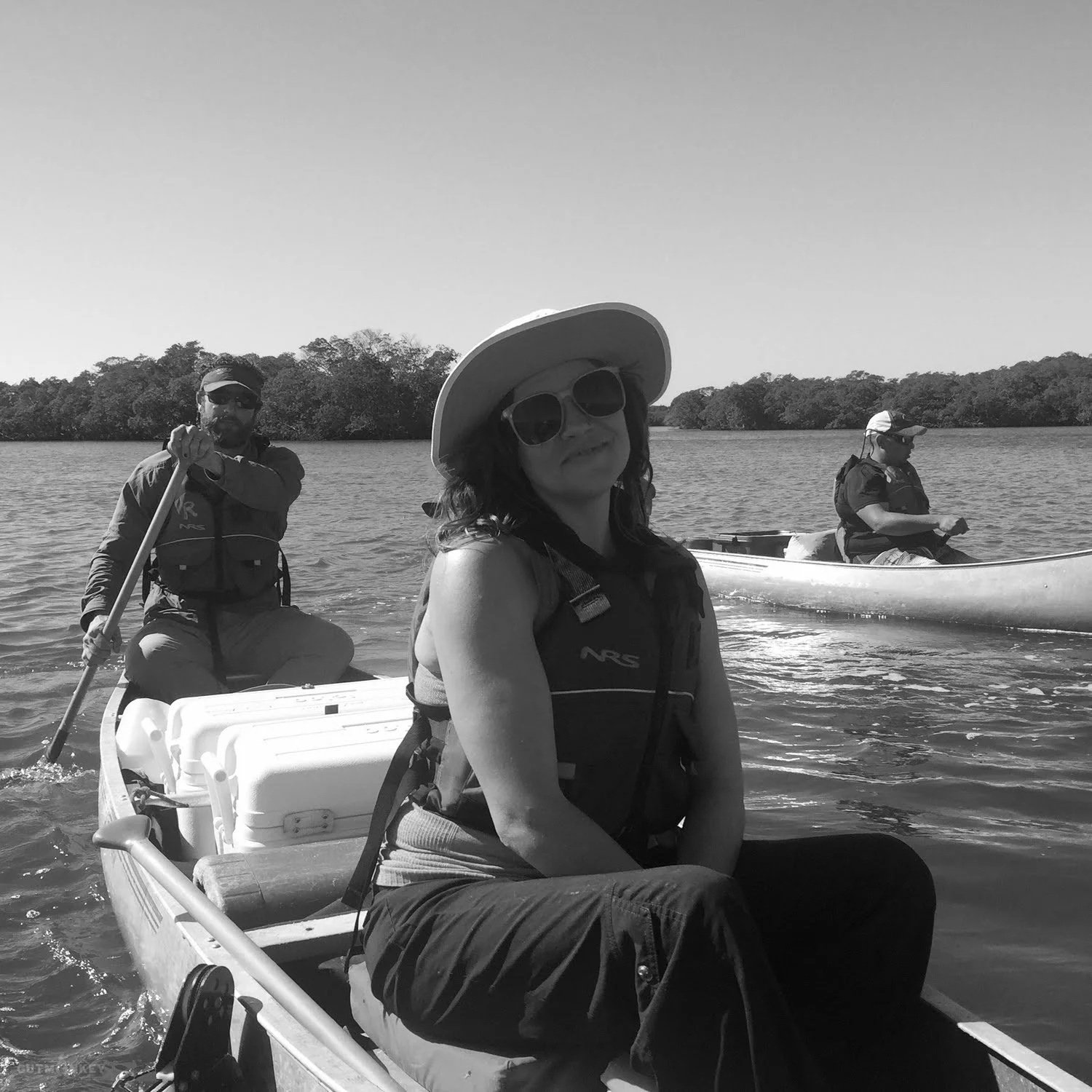 Woman relaxing in the front of a canoe while a guide paddles through the calm waterways of the Everglades’ Ten Thousand Islands.