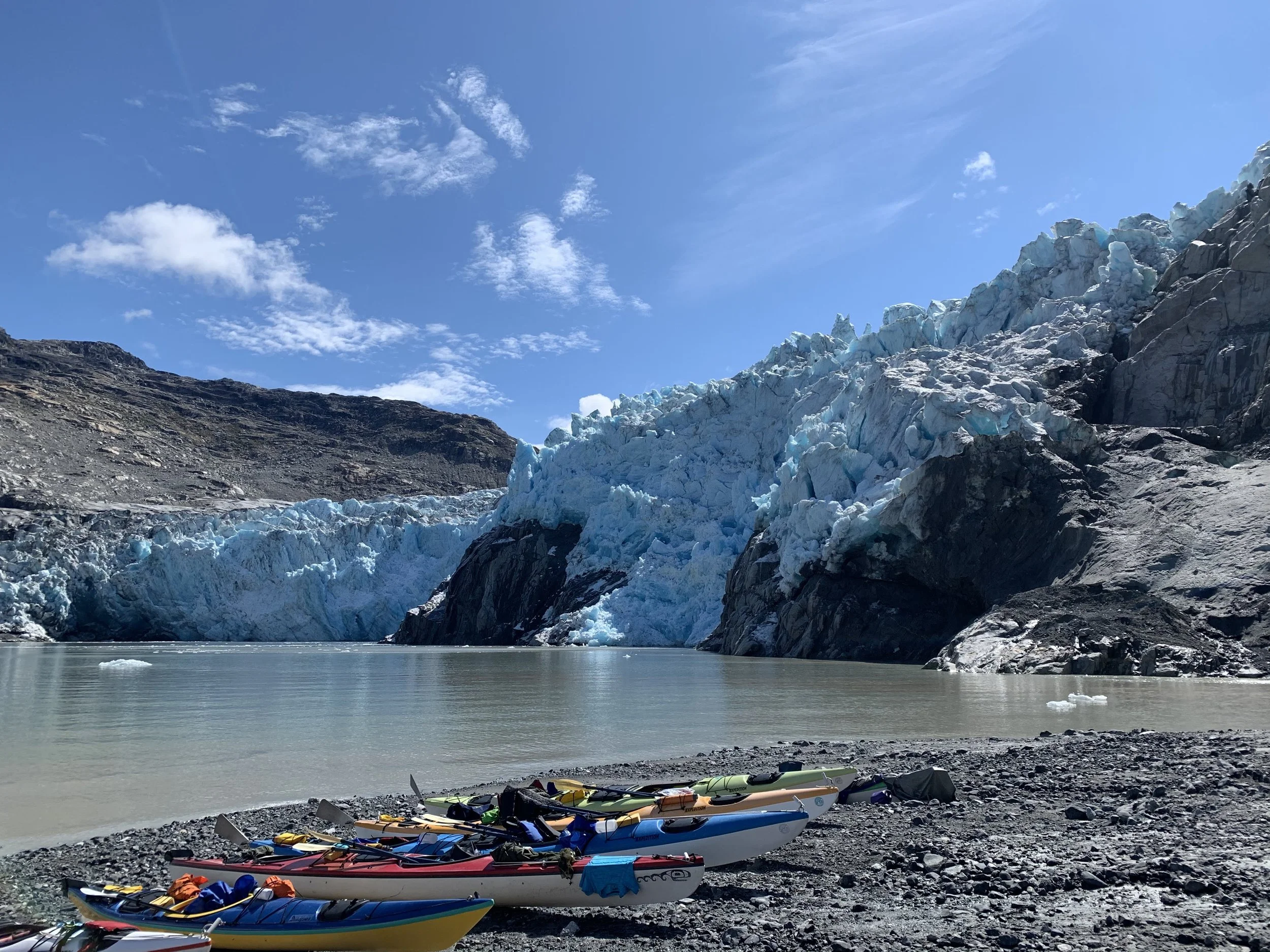 sea kayaks on the shore under a glacier in Alaska