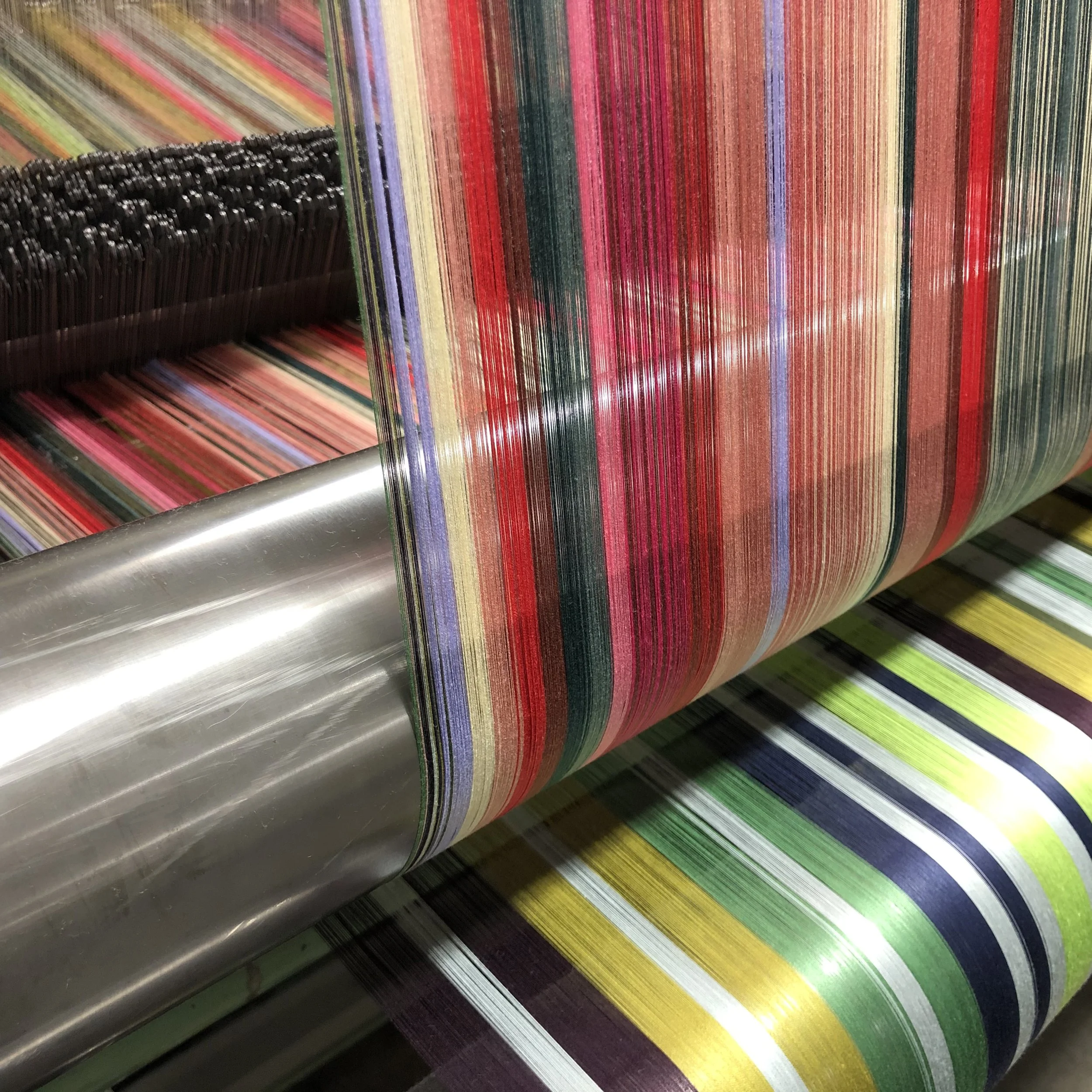 Yarns passing from double warp beams into the back of a loom. The two sets of yarns alternate coming to the face, creating a complex look