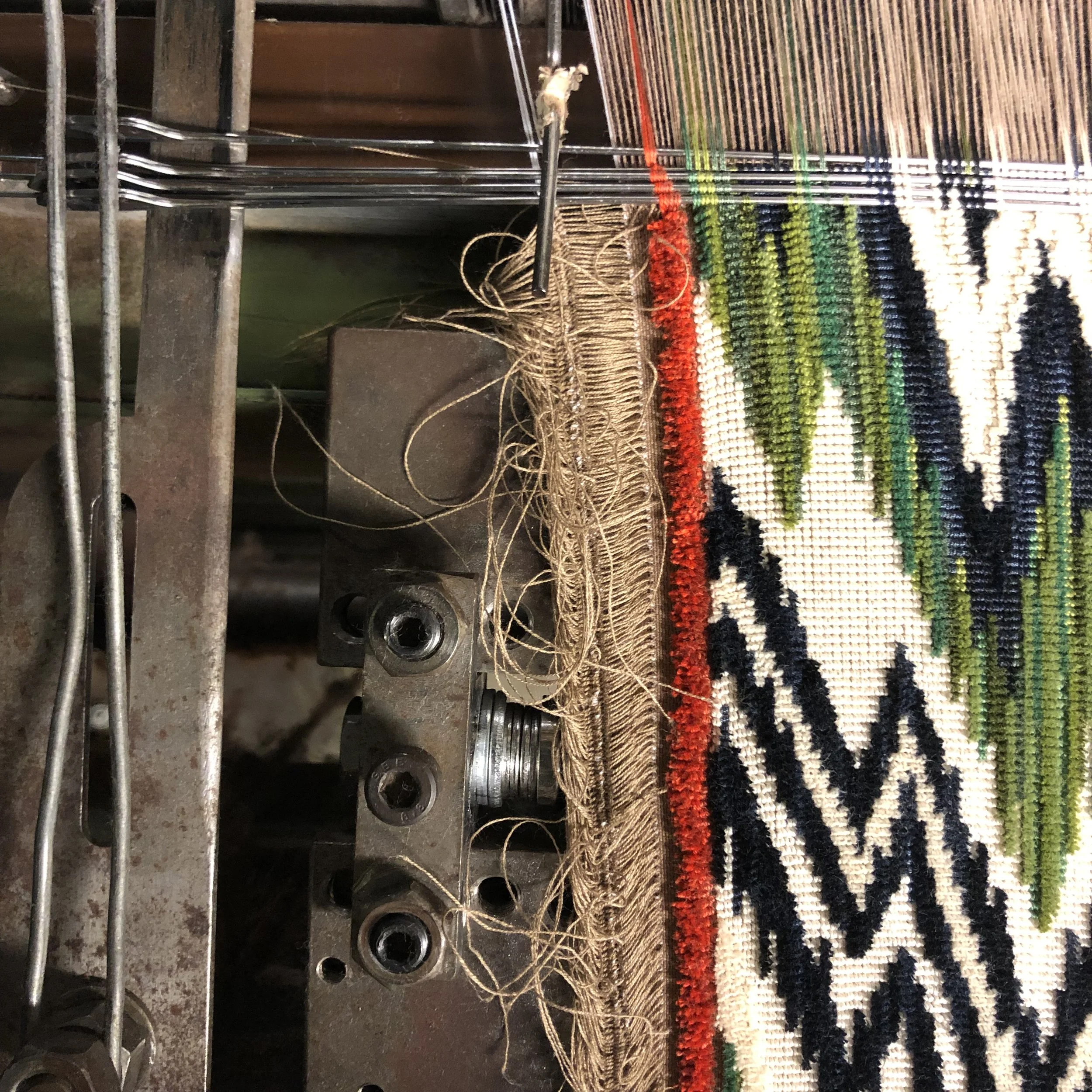 A cut and loop epinglé being woven on a wire loom, with the wires visible.