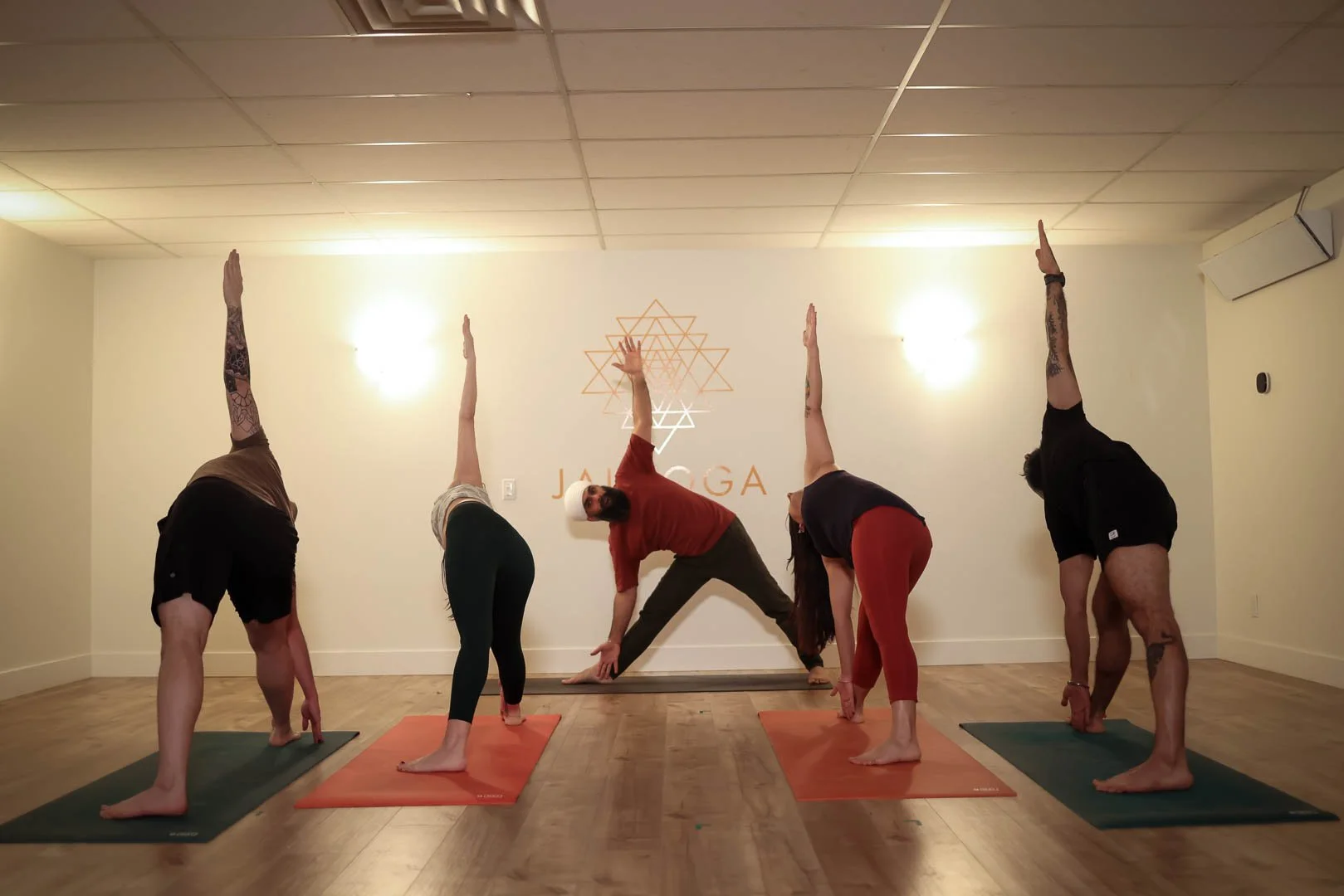 Students in yoga class stretching, promoting the 10-class yoga pass at Jai Yoga.
