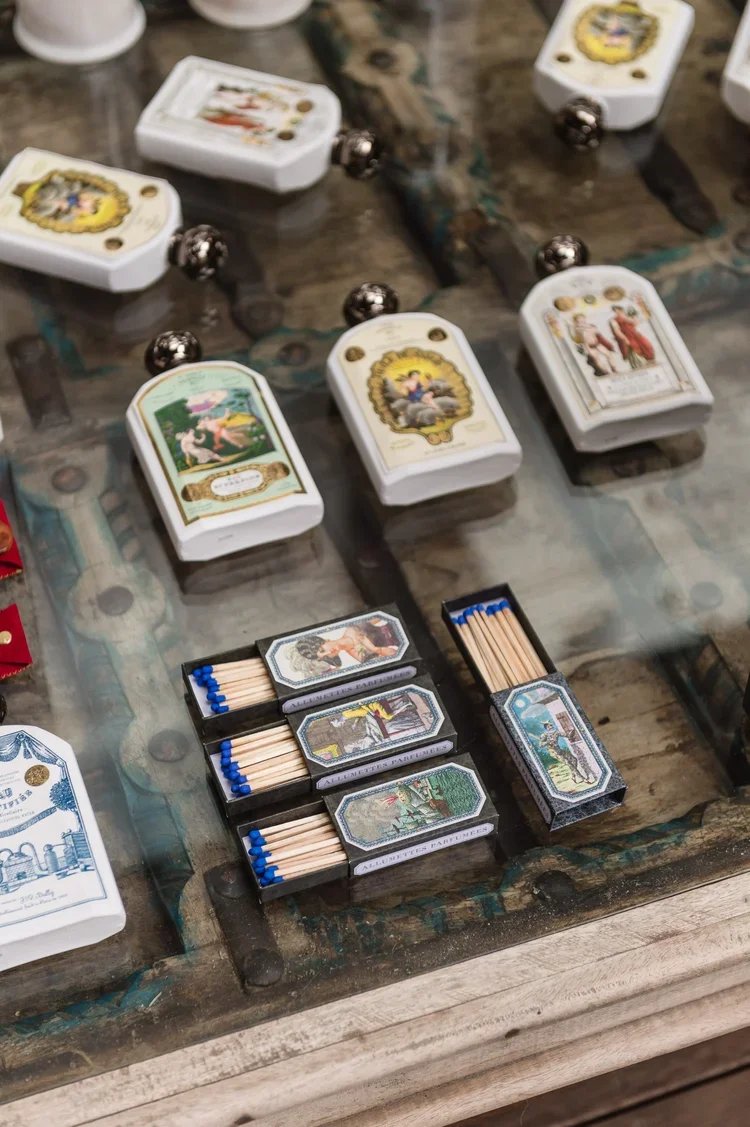 Vintage-style playing cards and matchboxes with artwork of classic scenes, arranged on a rustic wooden table.