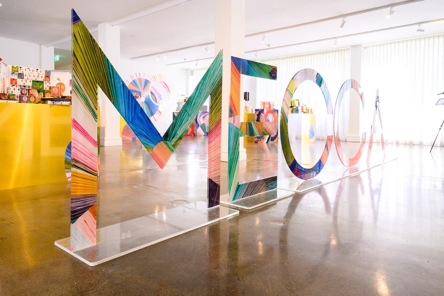 Colorful, artistic 3D letters spelling out 'ME' in an art gallery.
