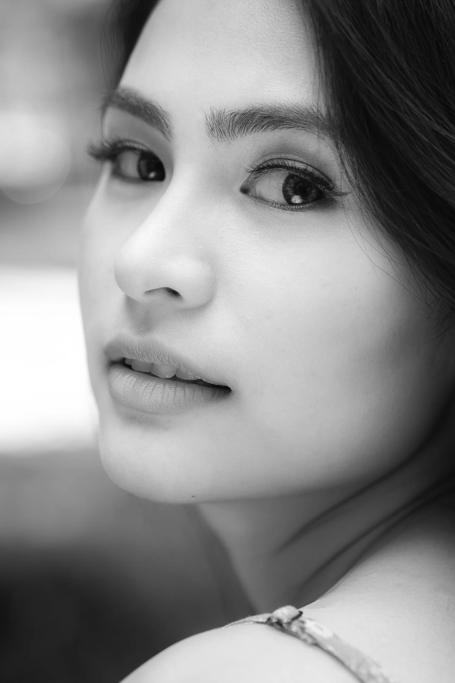 Intimate black-and-white close-up portrait of a woman looking over her shoulder.