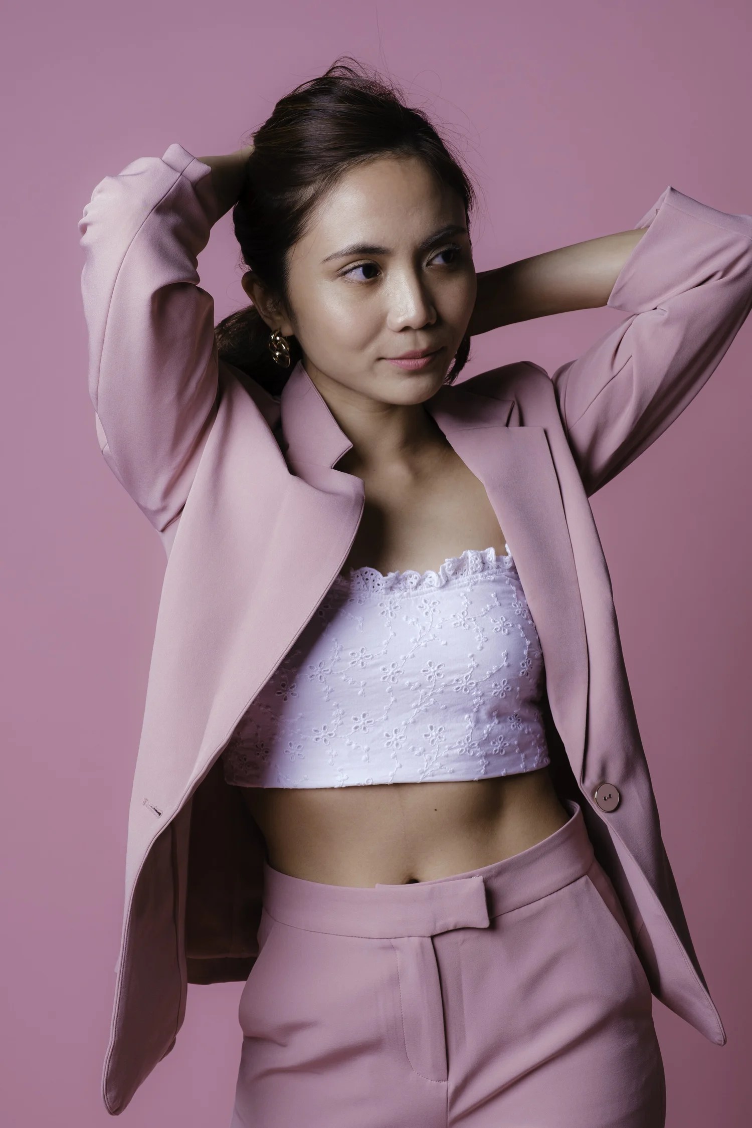 Studio portrait of a woman in a pink suit against a pink background.