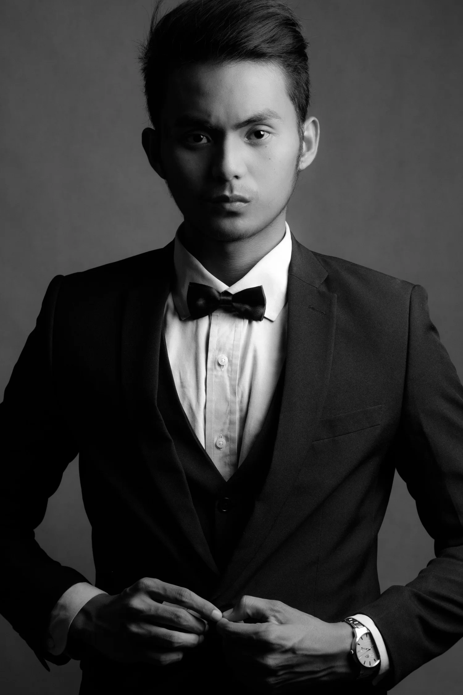 Dramatic black-and-white portrait of a man in a tuxedo with directional lighting.