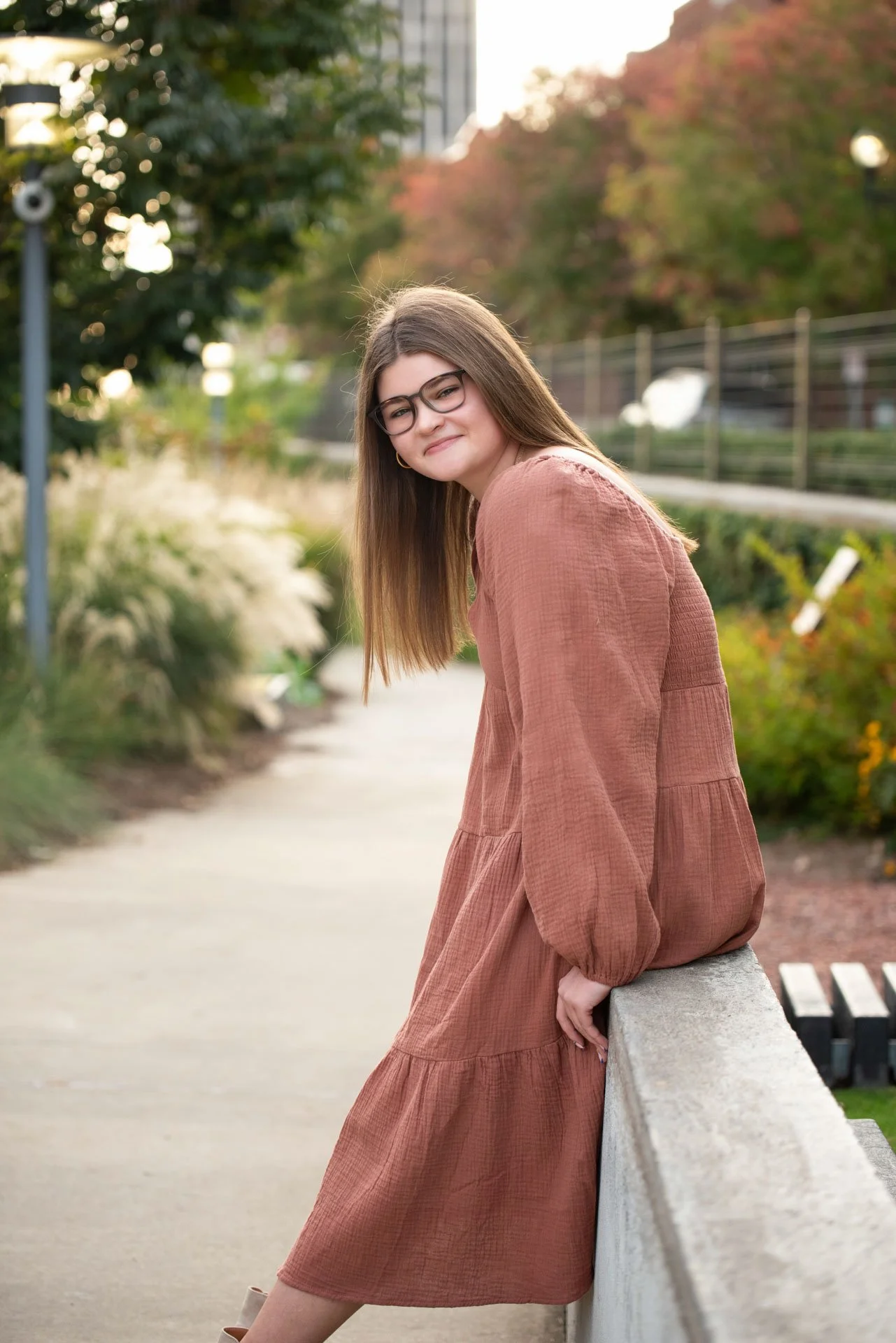 Senior girl in rust dress leaning on railing with fall foliage in Birmingham Alabama, Darling Dear Photo