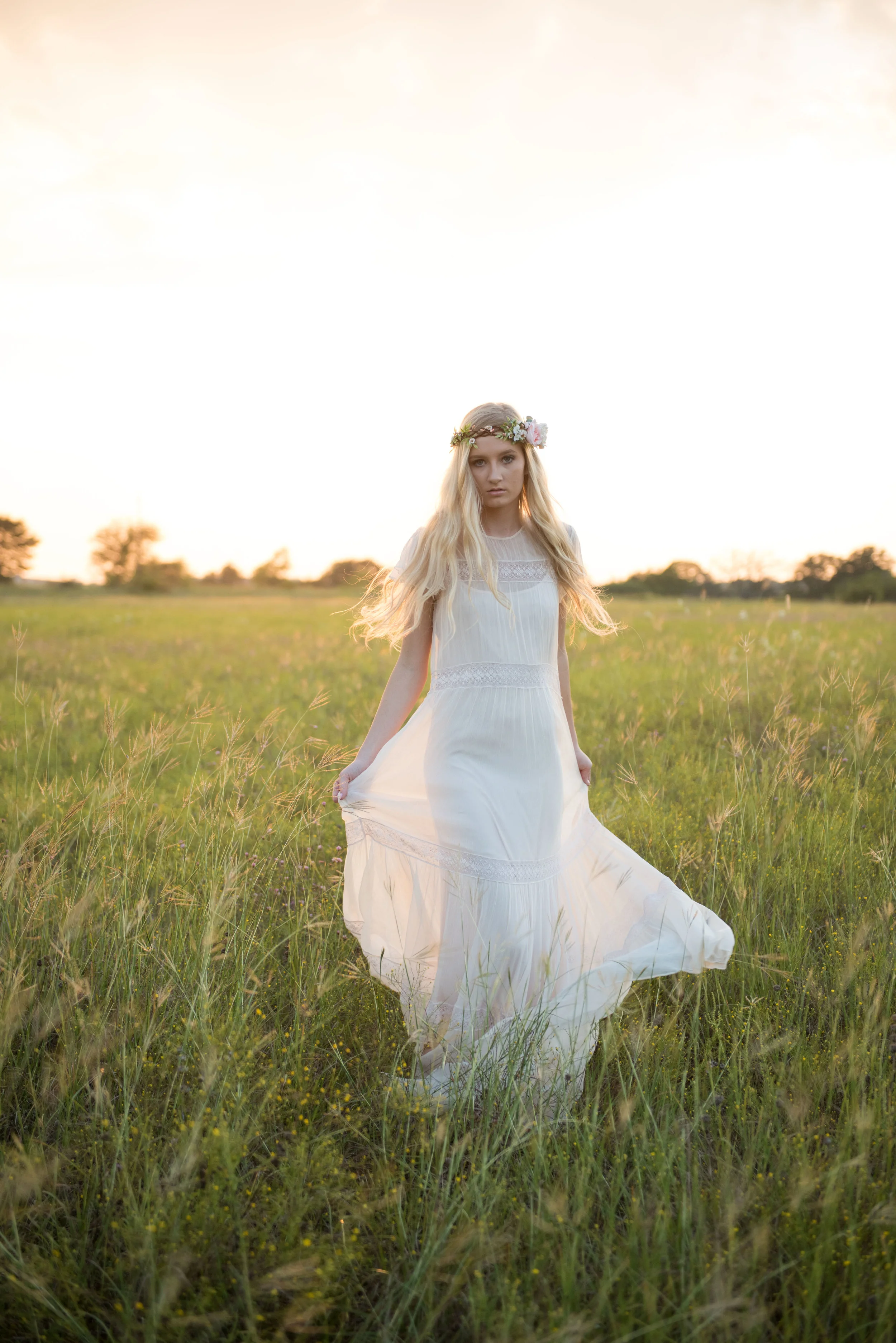 girl in white dress twirling in a field of grass in outdoor pell city high school senior session