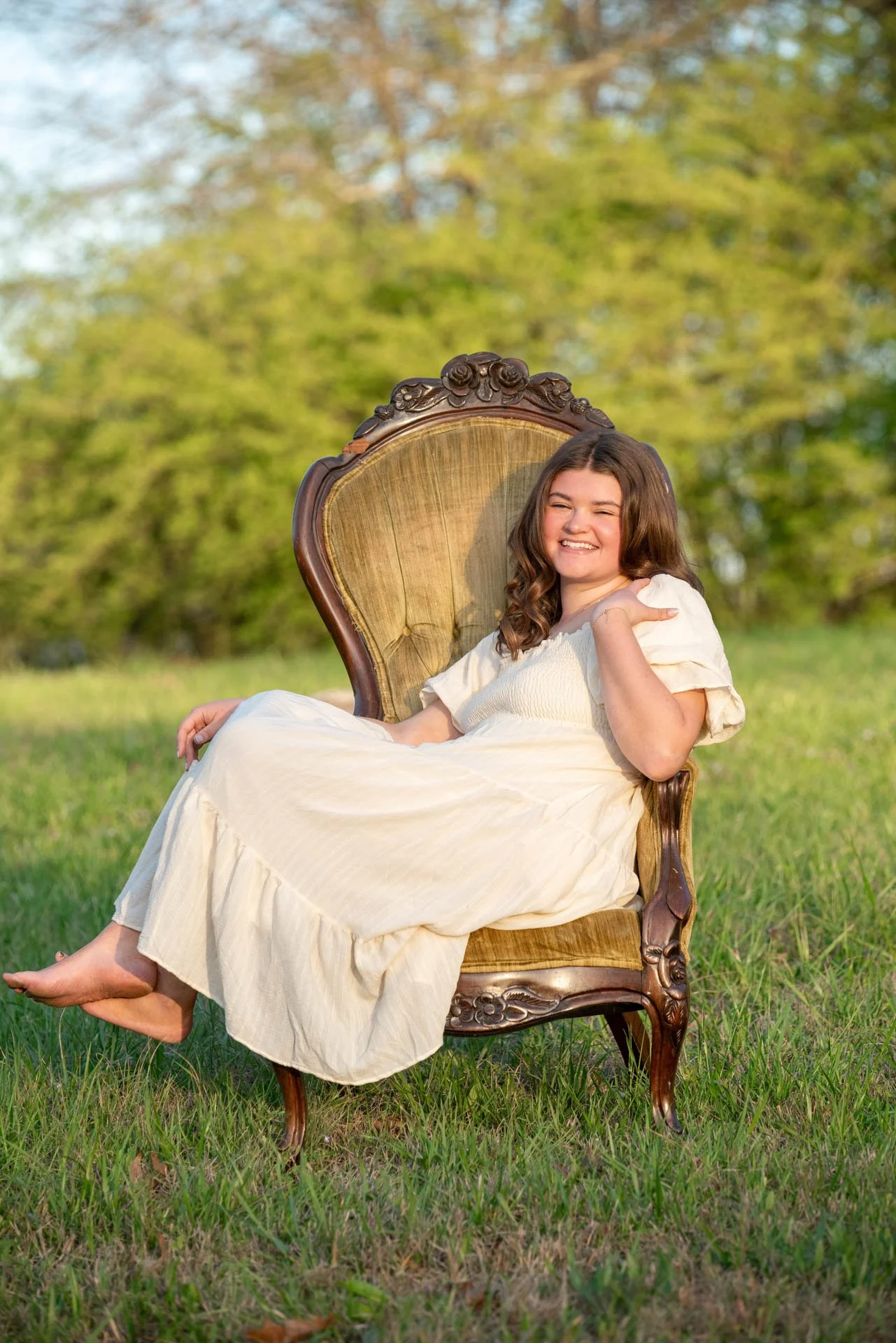 Senior girl laughing in vintage chair in Alabama field at golden hour, Pell City senior photography by Darling Dear Photo