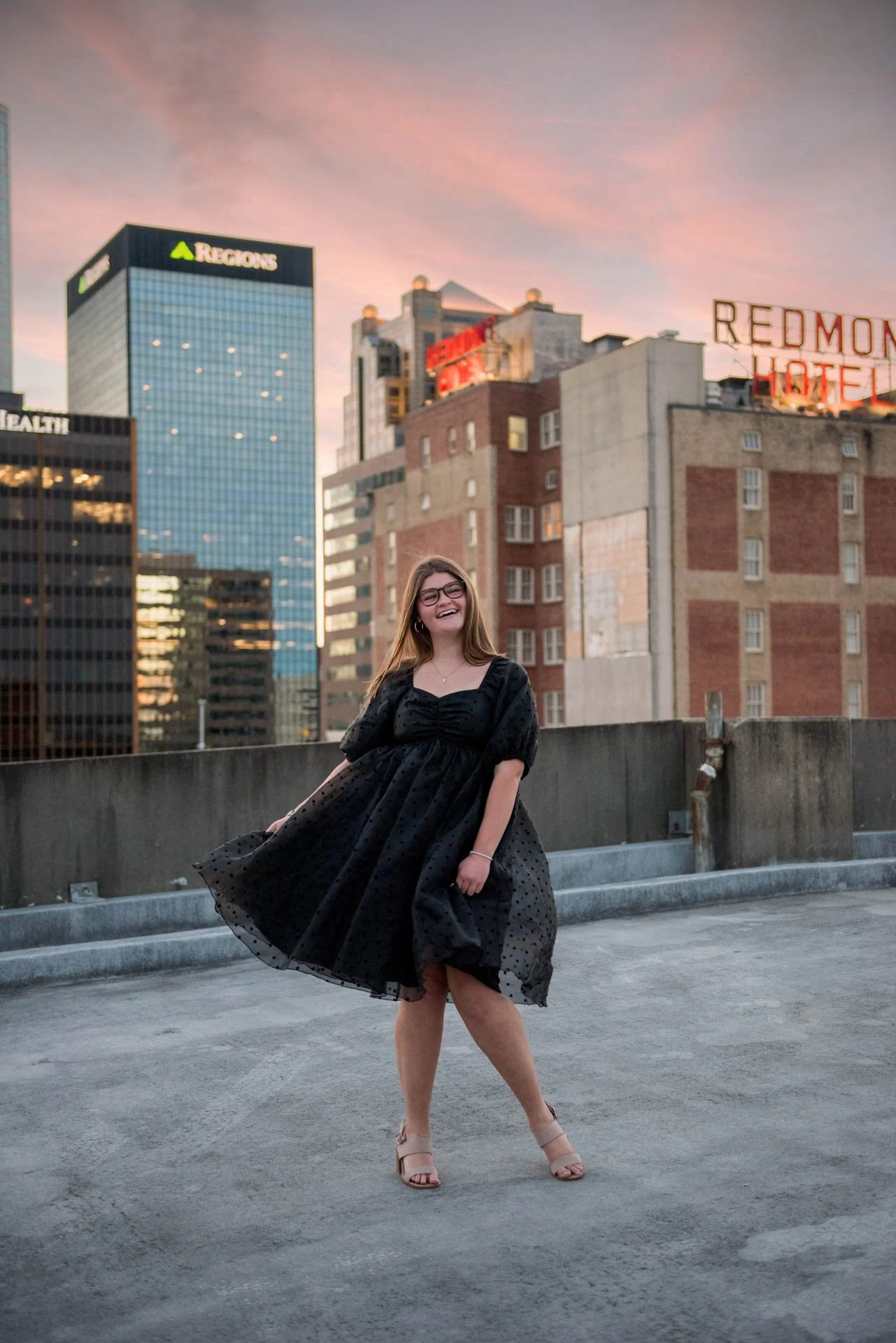 High school senior twirling in black dress on Birmingham Alabama rooftop at sunset, Darling Dear Photo