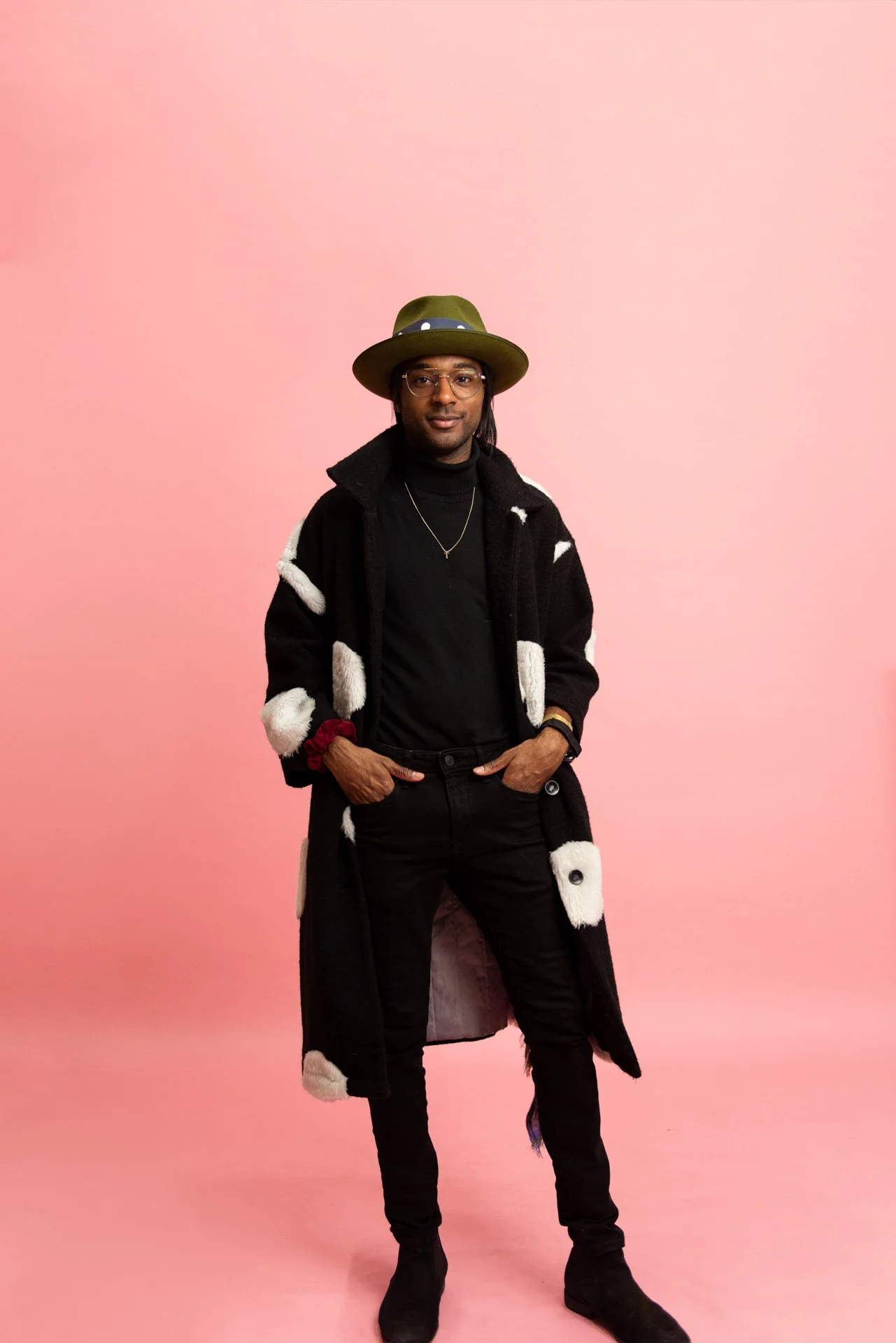 darling & dear branding client on pink backdrop in long black and white fur coat and green hat for high fashion personal brand