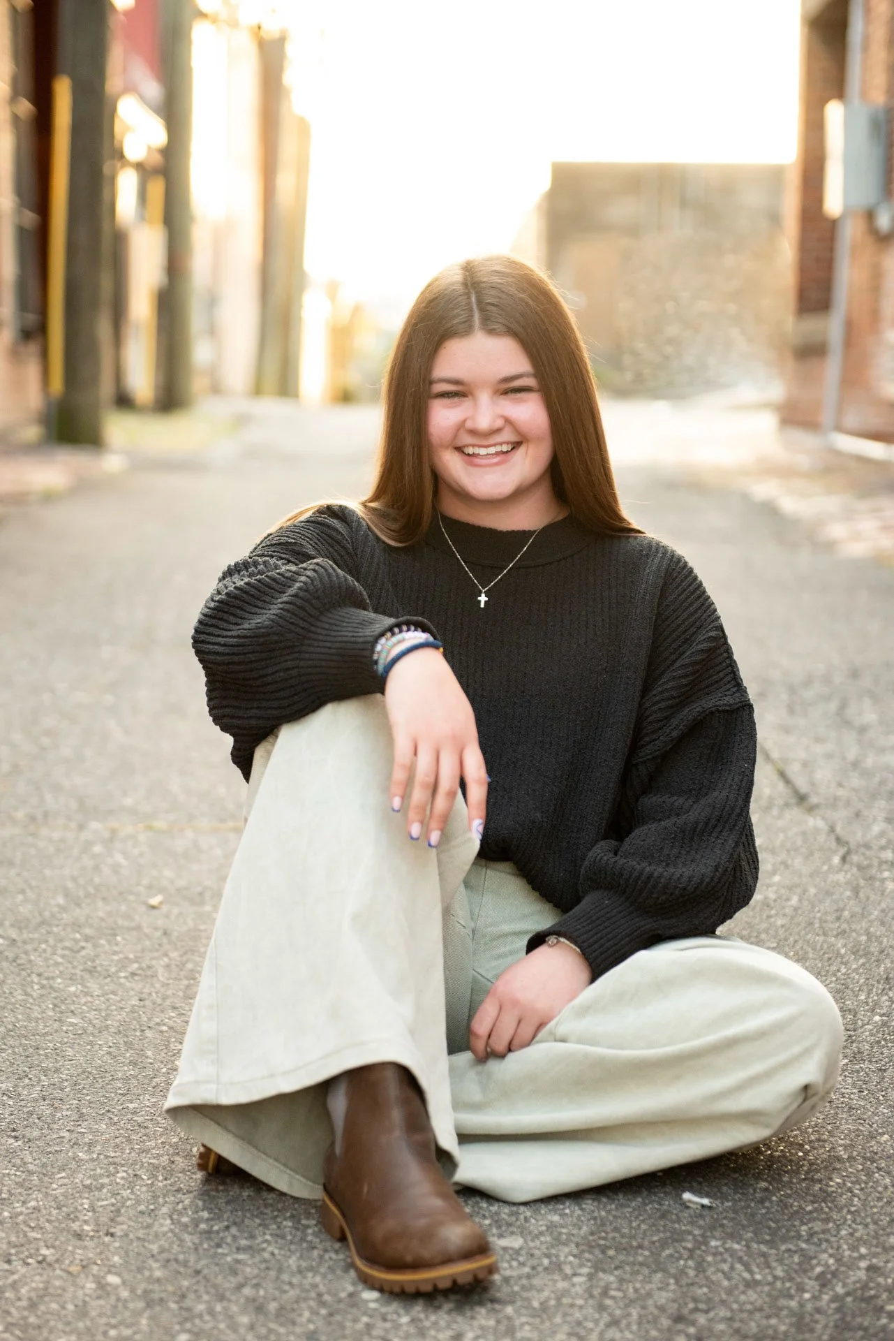 Senior girl sitting in golden hour Birmingham Alabama alley in black sweater and wide leg pants, Darling Dear Photo