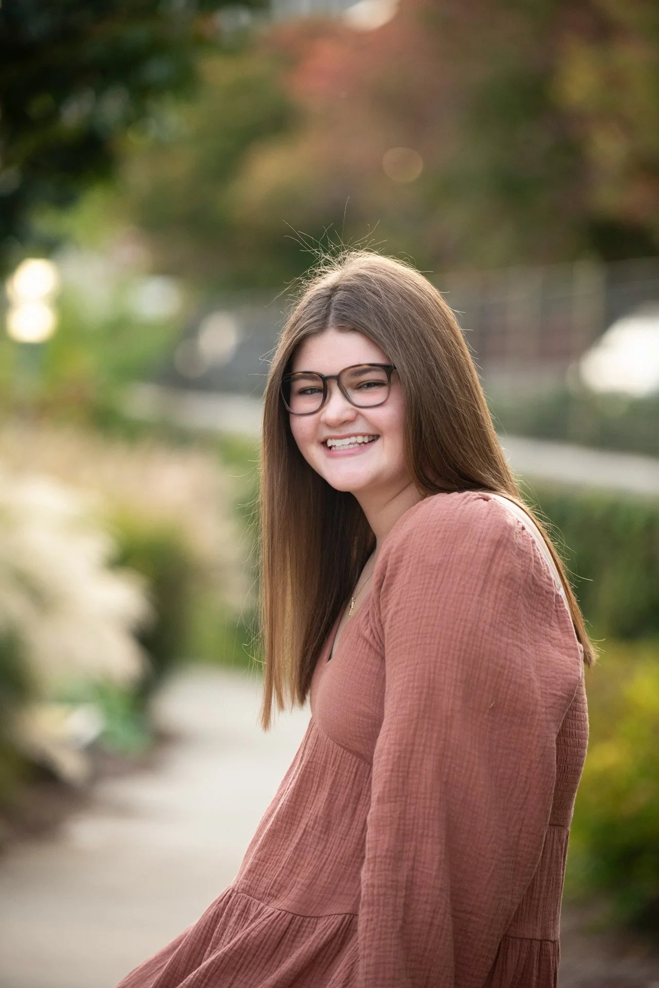 High school senior in rust dress laughing over her shoulder in Birmingham Alabama garden, Darling Dear Photo