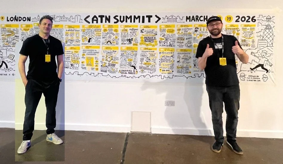 Two men standing in front of a large illustrated timeline wall at the ATN Summit 2026 in London, March 19, 2026. One man is on the left with hands in pockets, and the other on the right giving thumbs up.
