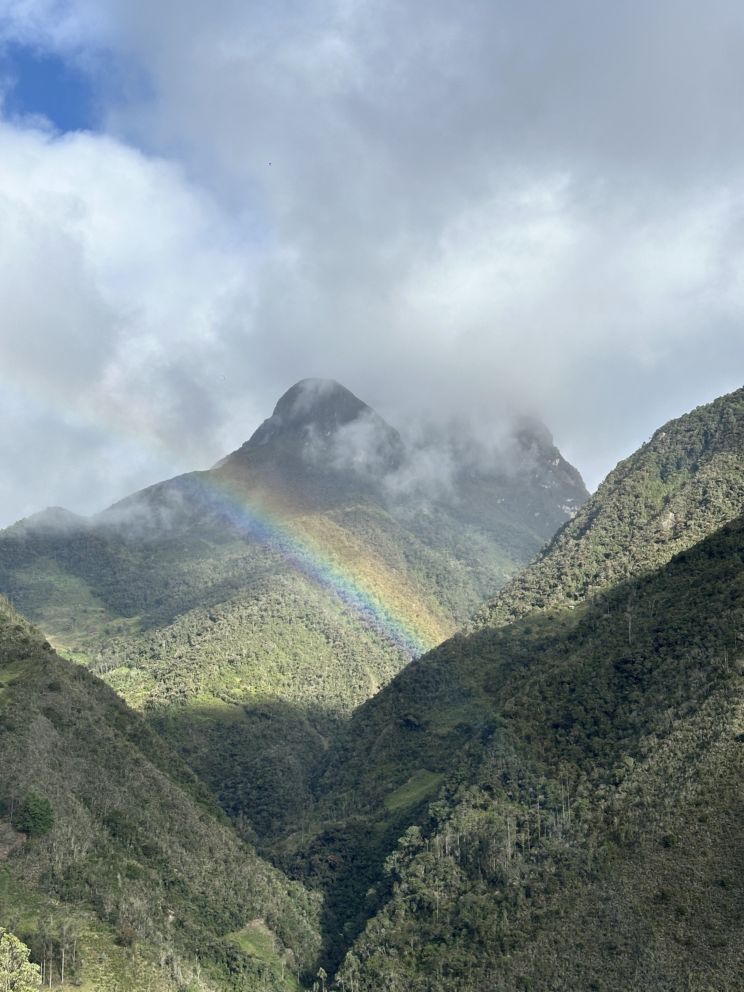 Montañas verdes con un arcoíris y nubes en el cielo