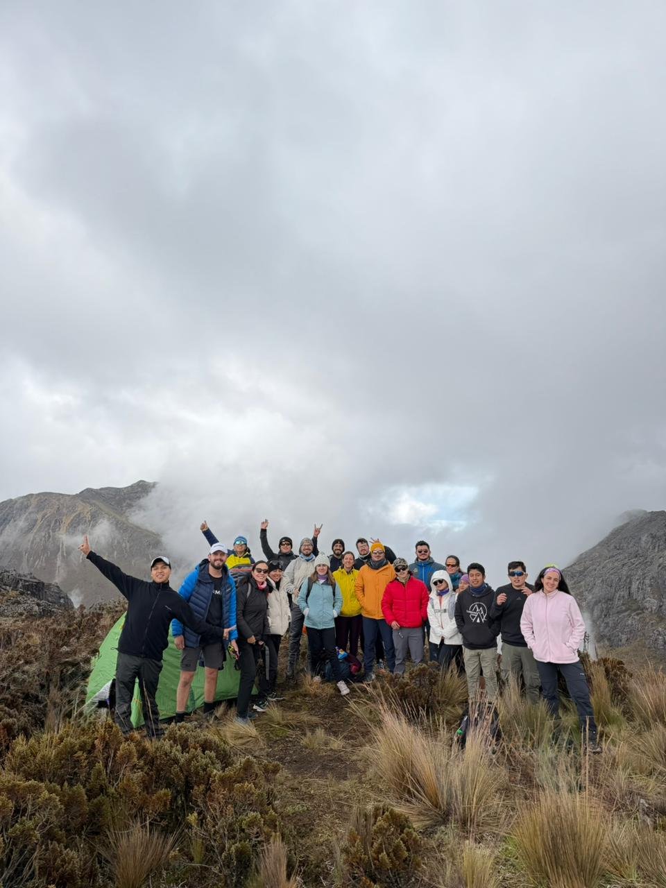 Grupo de personas en una caminata en la montaña, con un cielo nublado.