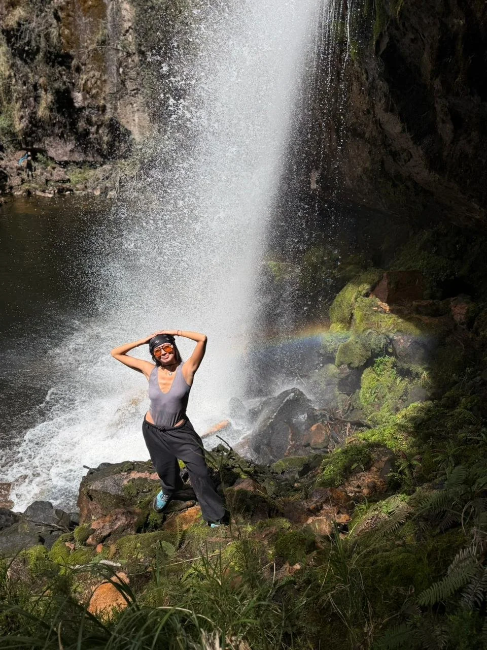 Mujer sonriendo en la naturaleza junto a una cascada.