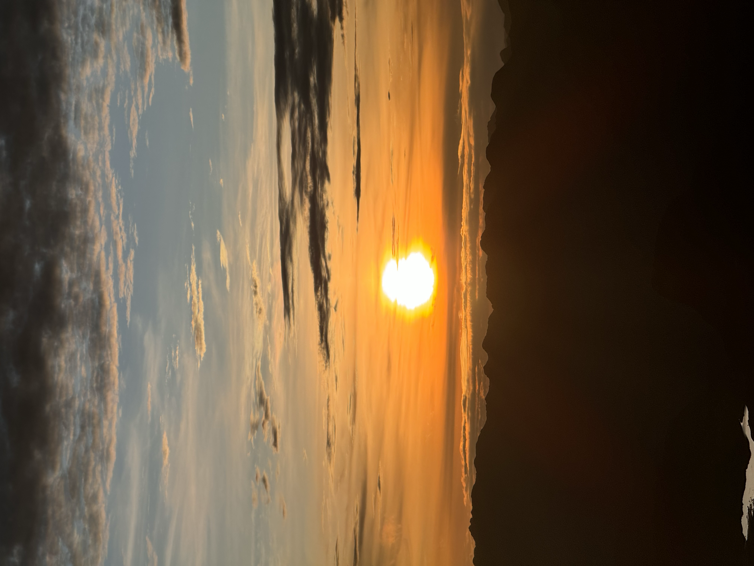 Atardecer sobre un lago con nubes dispersas y montañas en el horizonte.