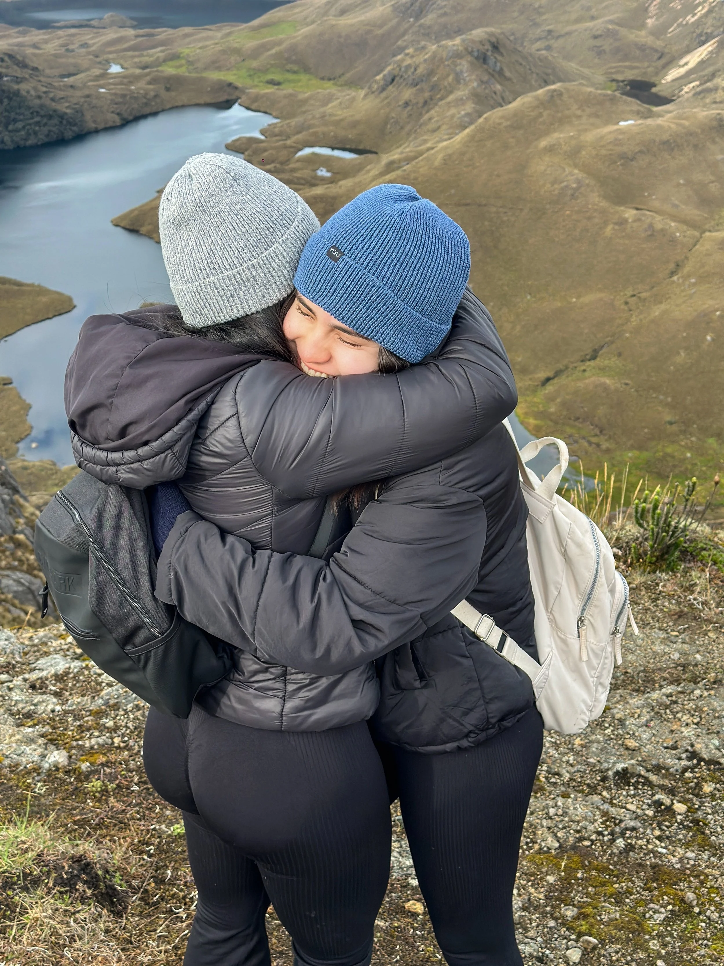 Dos personas abrazándose en un paisaje montañoso con lagos.