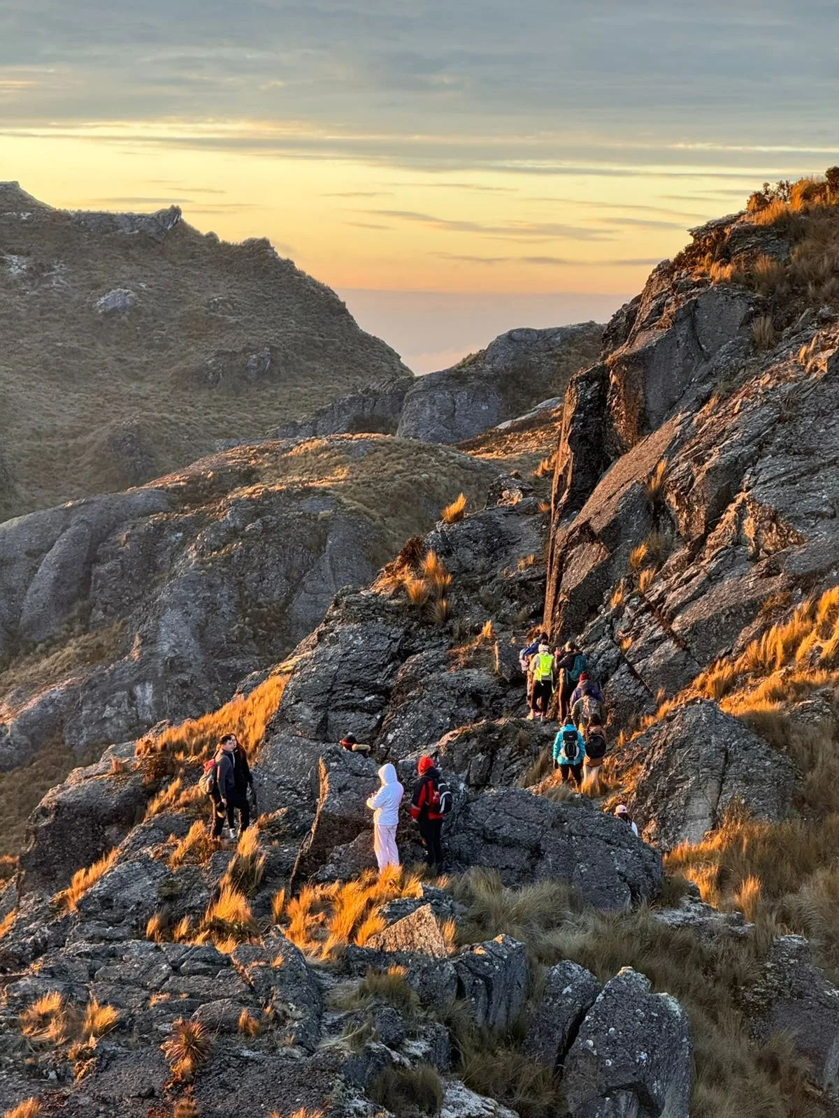 Grupo de personas haciendo senderismo en una montaña durante el atardecer