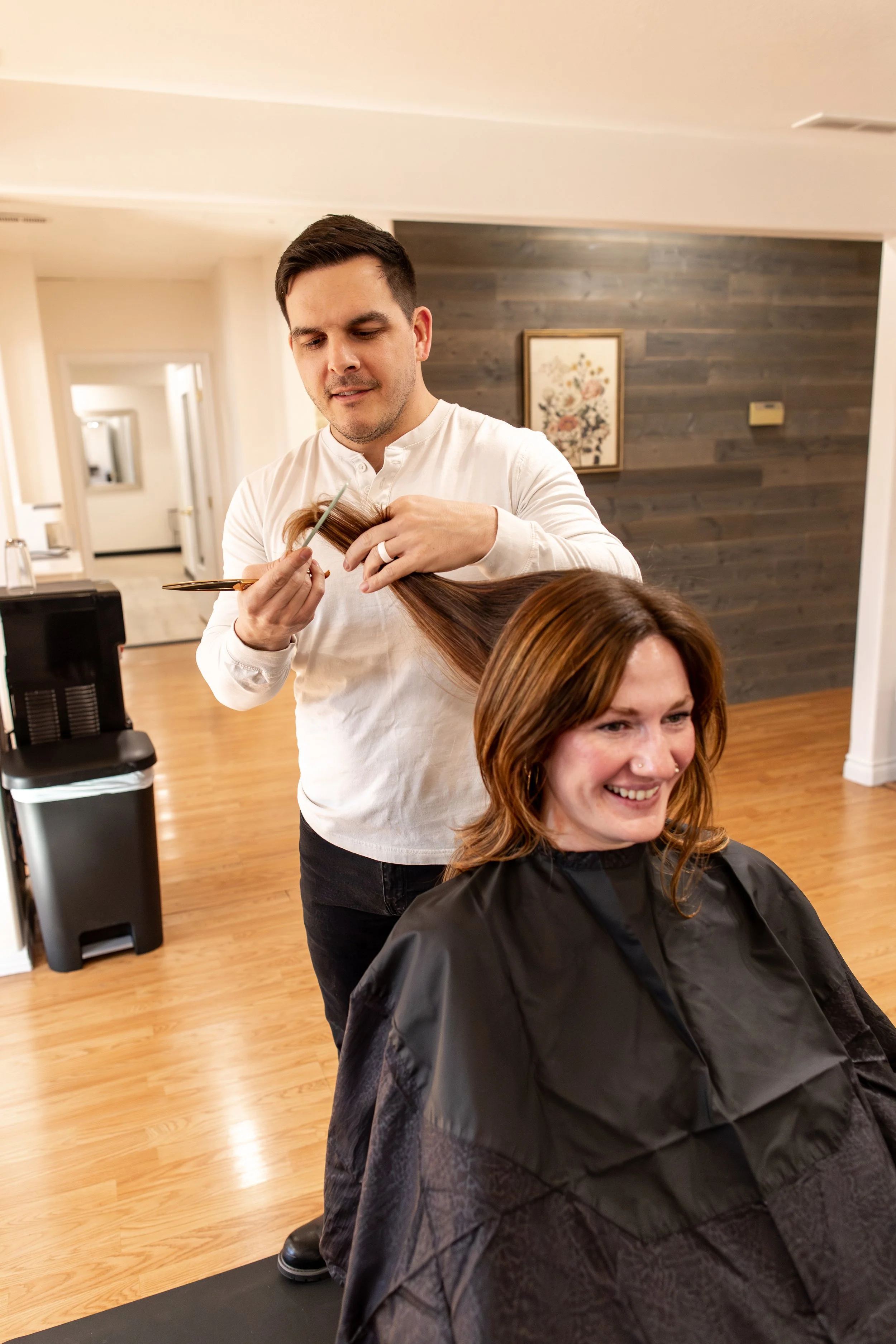 Male hairstylist styling or curling female client's long blonde hair in a salon