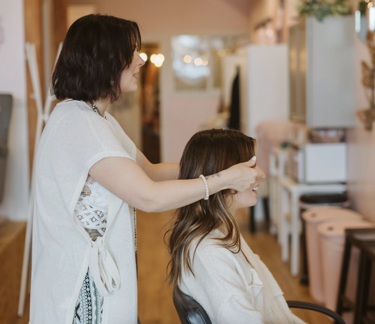 A woman receiving a manicure at a salon, with her hands being painted by a technician.