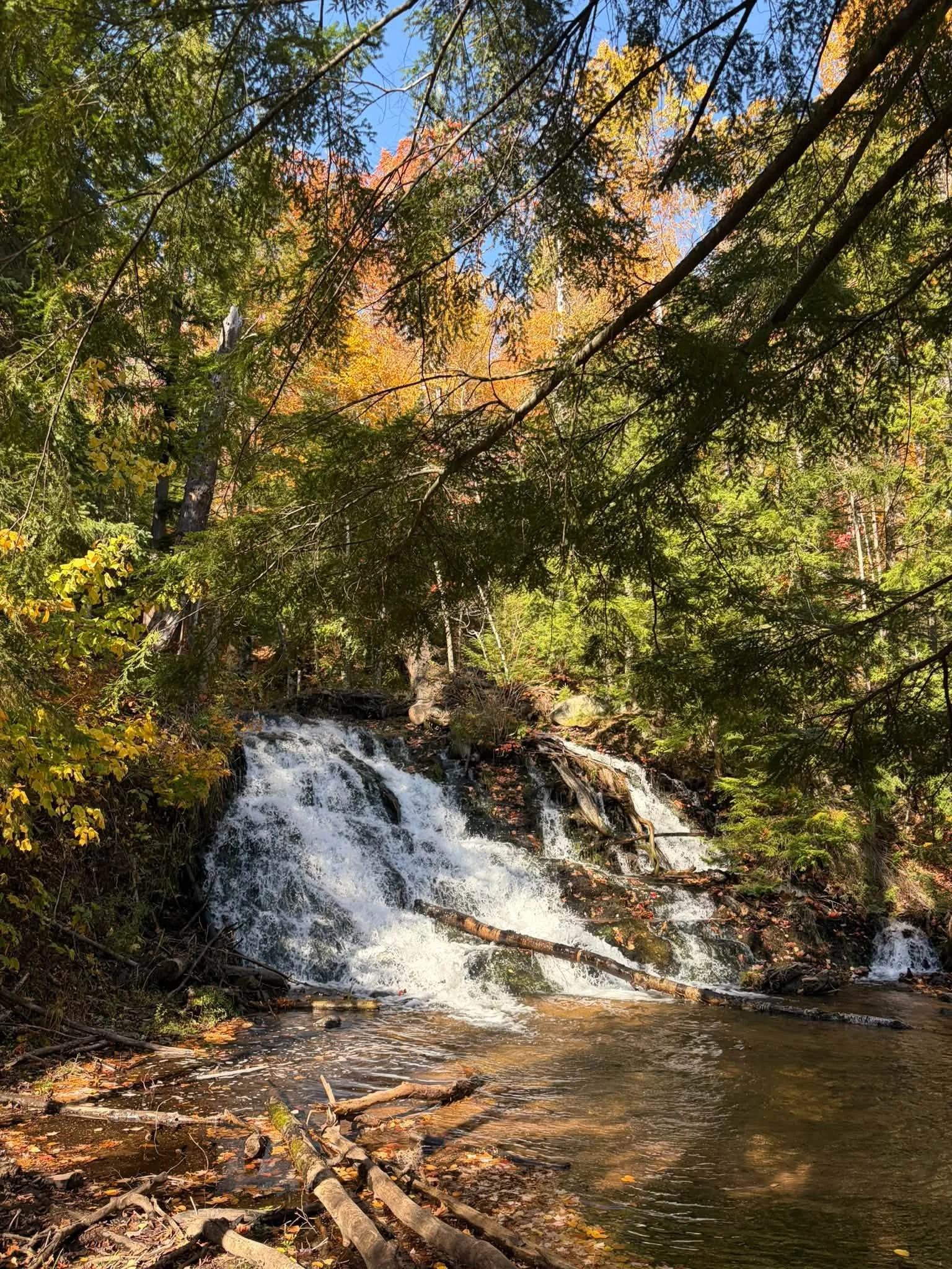 Waterfall flowing over rocks through a forest with autumn foliage near Marquette, Michigan.
