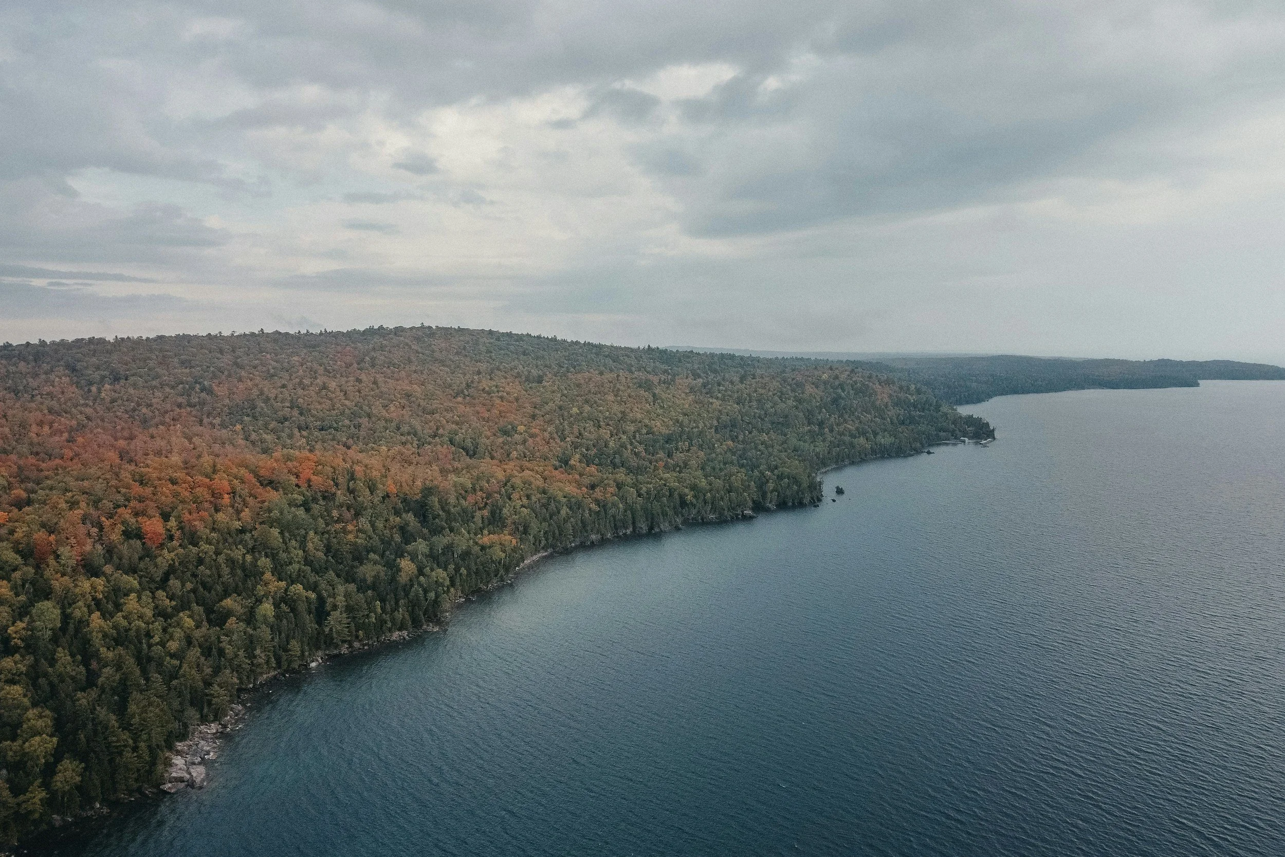 Aerial view of Lake Superior and the forested shoreline in Michigan’s Upper Peninsula during fall.