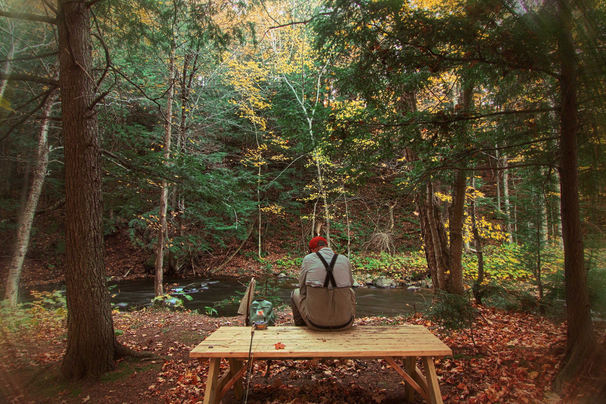 Man sitting on picnic table fishing Rippling River Resort
