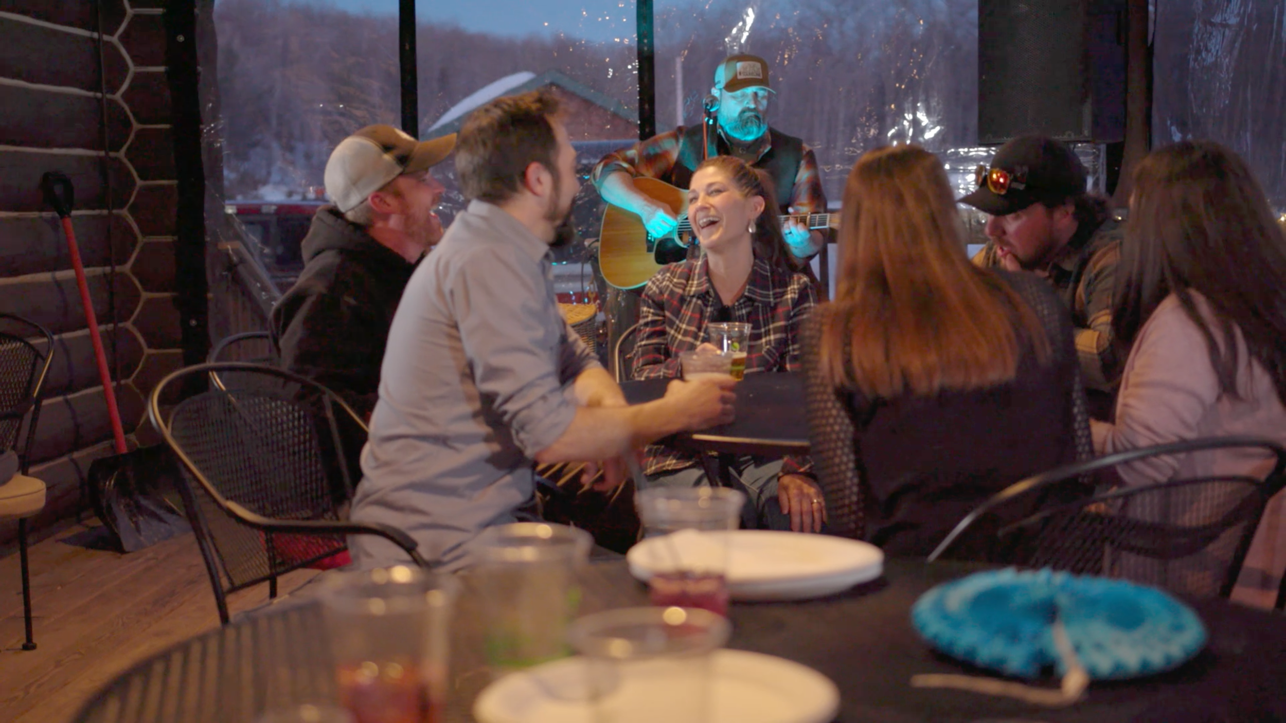 People laughing and having drinks on the patio while listening to live music at Junkfish Tavern Rippling River Marquette