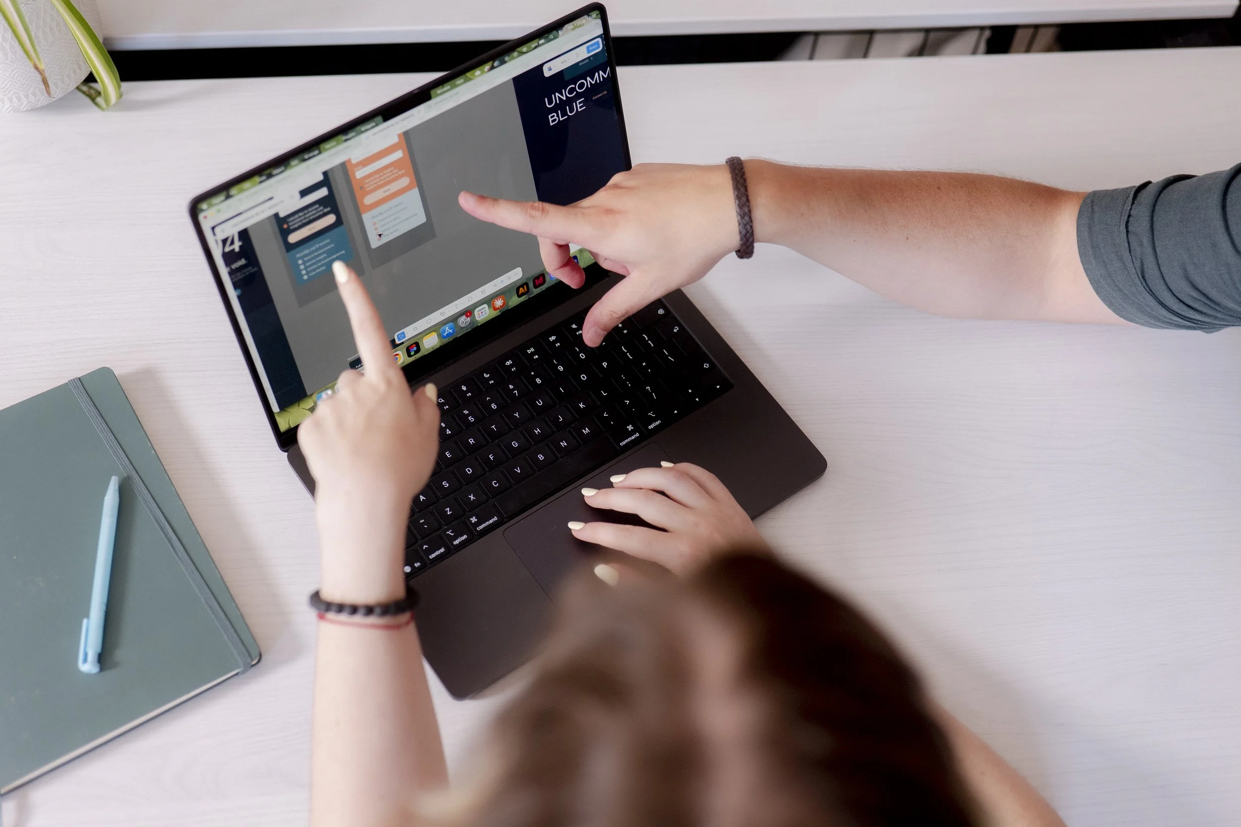 hand pointing to laptop screen displaying the work on the screen.