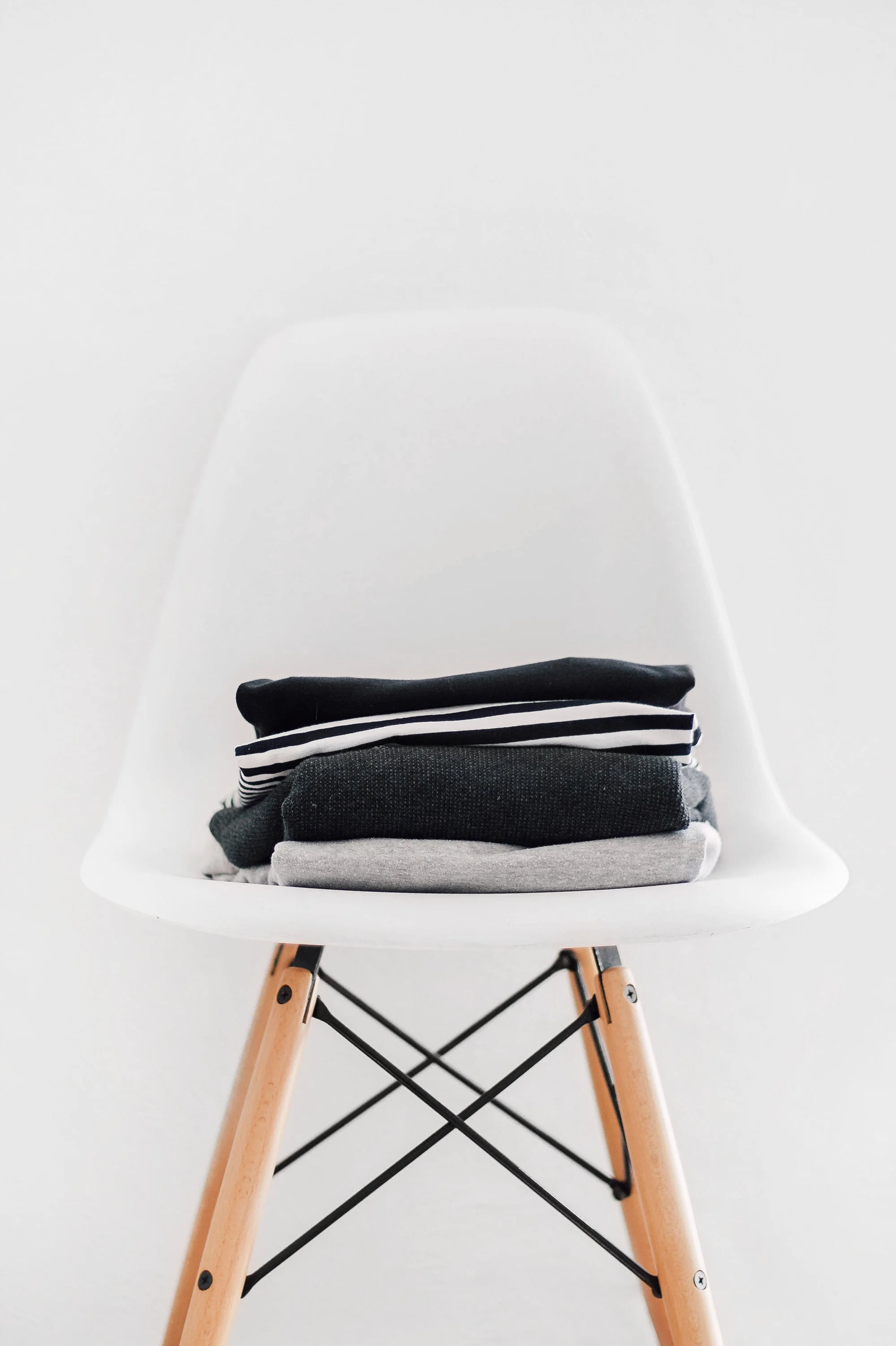 4-pile-of-sweaters-on-white-eames-chair.jpg