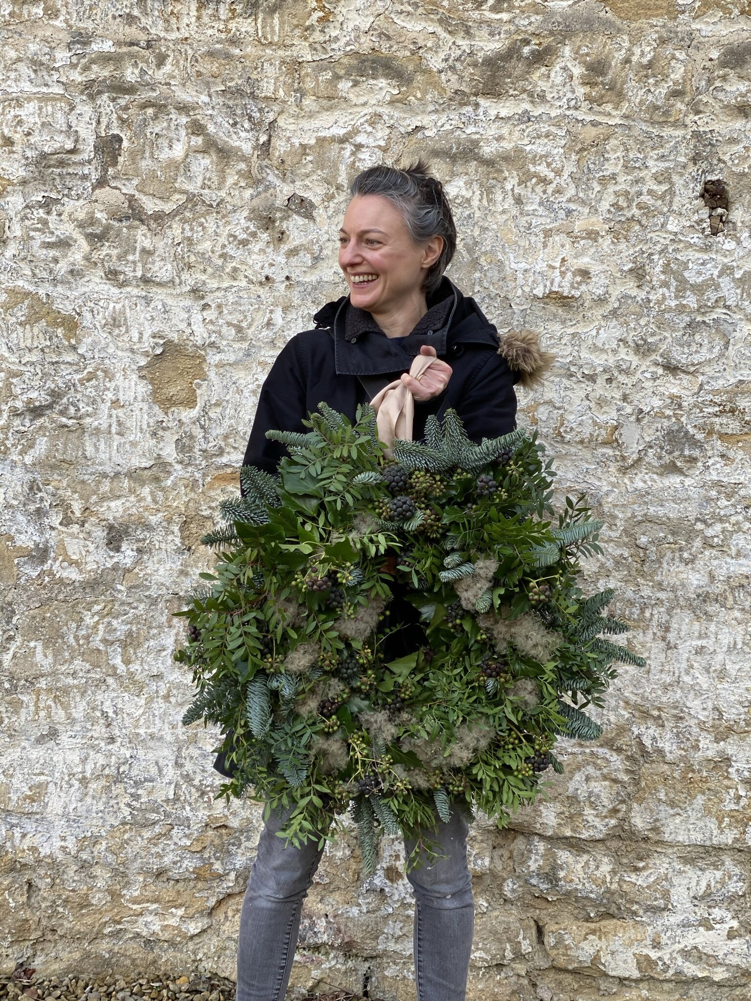Hedgerow inspired Christmas wreath being held by student in front of a brick wall (Copy)
