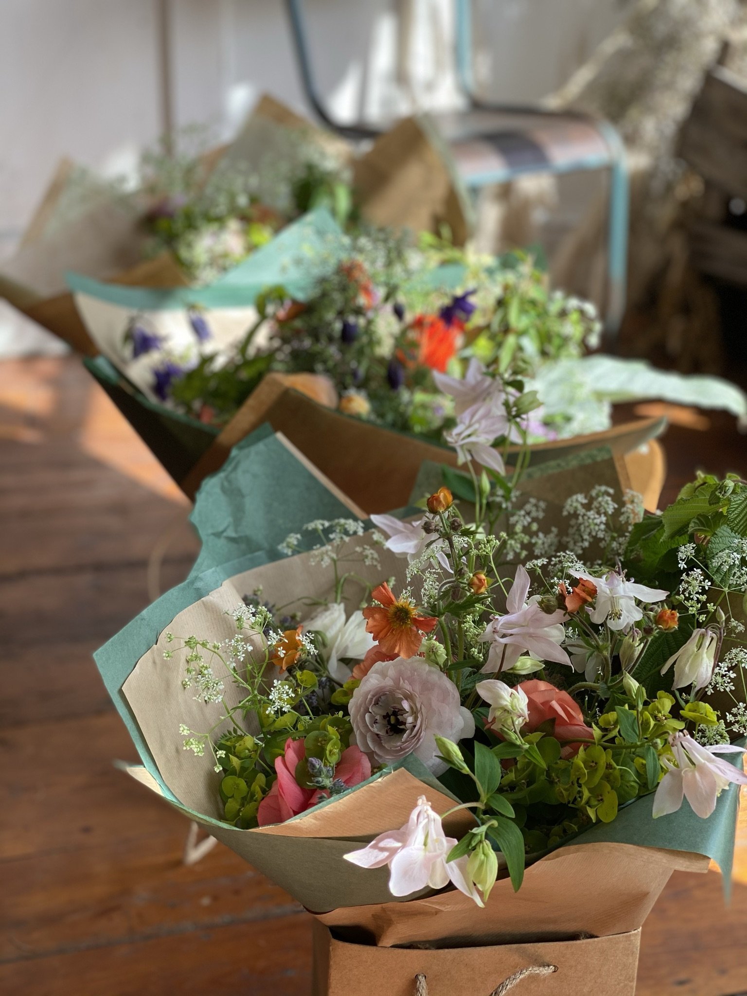 A line up of beautifully packaged hand tied bouquets on a wooden floor