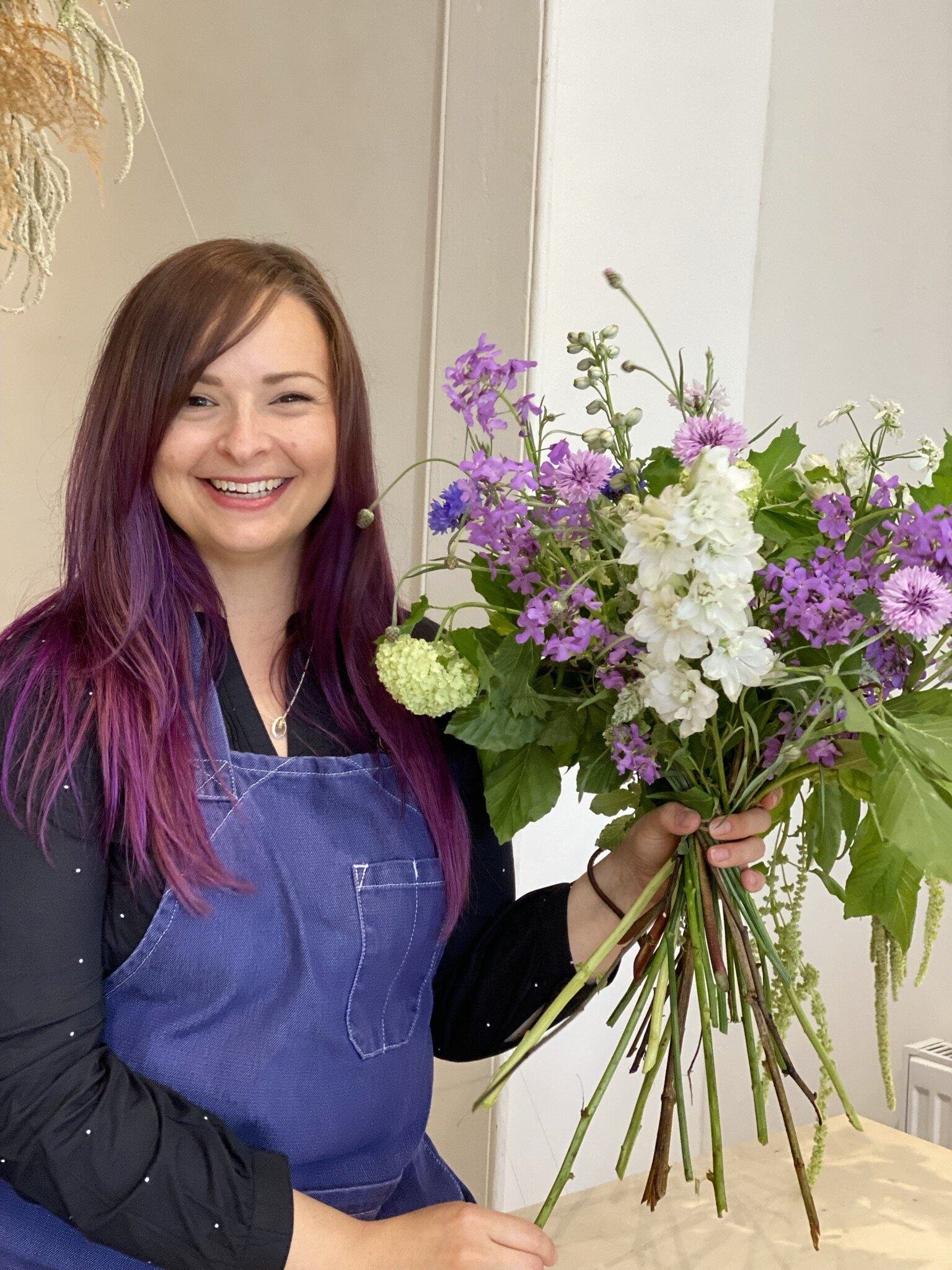 Student look happy, holding a seasonal summers bouquet of flowers made at The Bath Flower School 