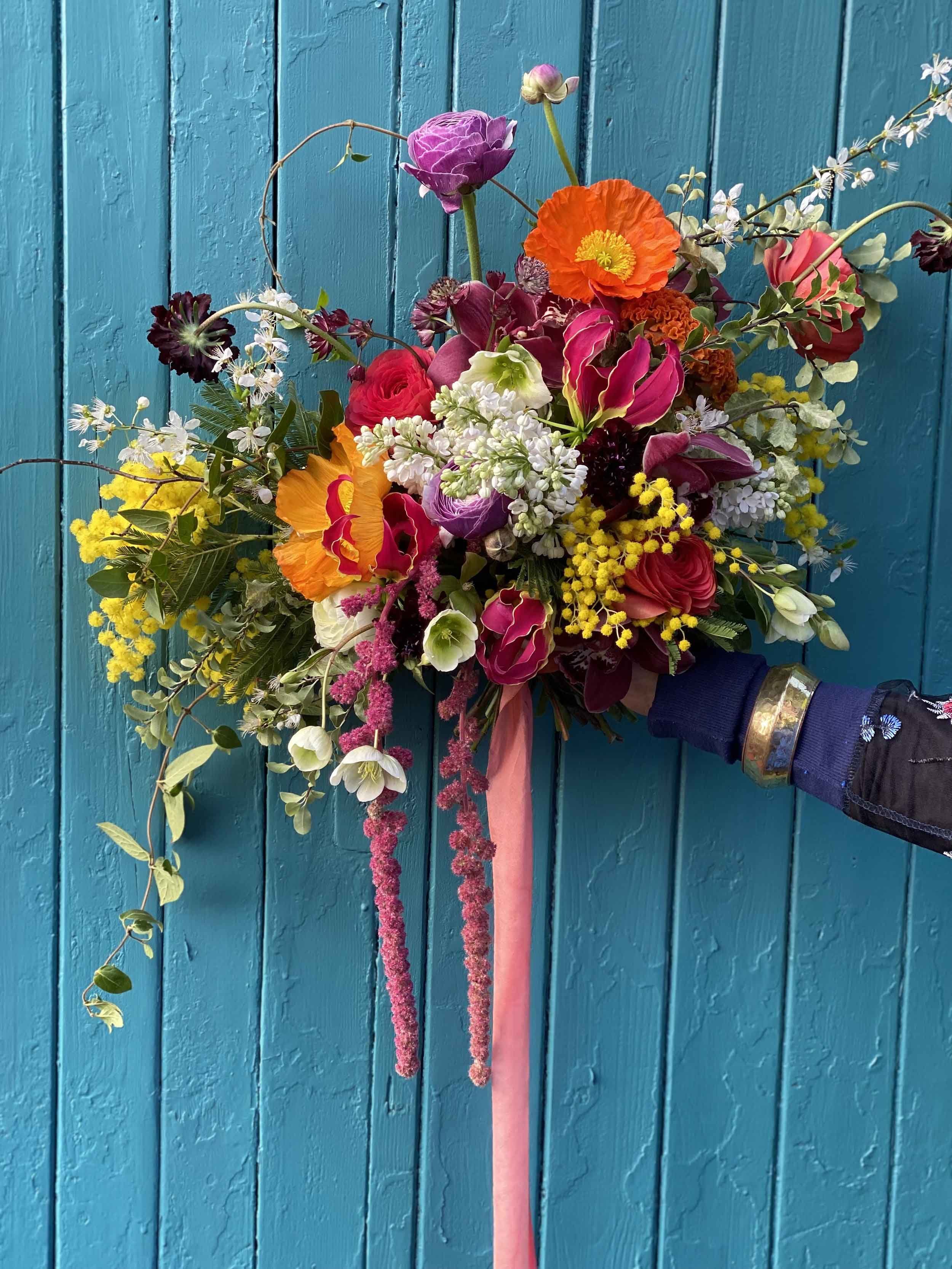 Brightly coloured bridal bouquet showcased against a blue wooden background