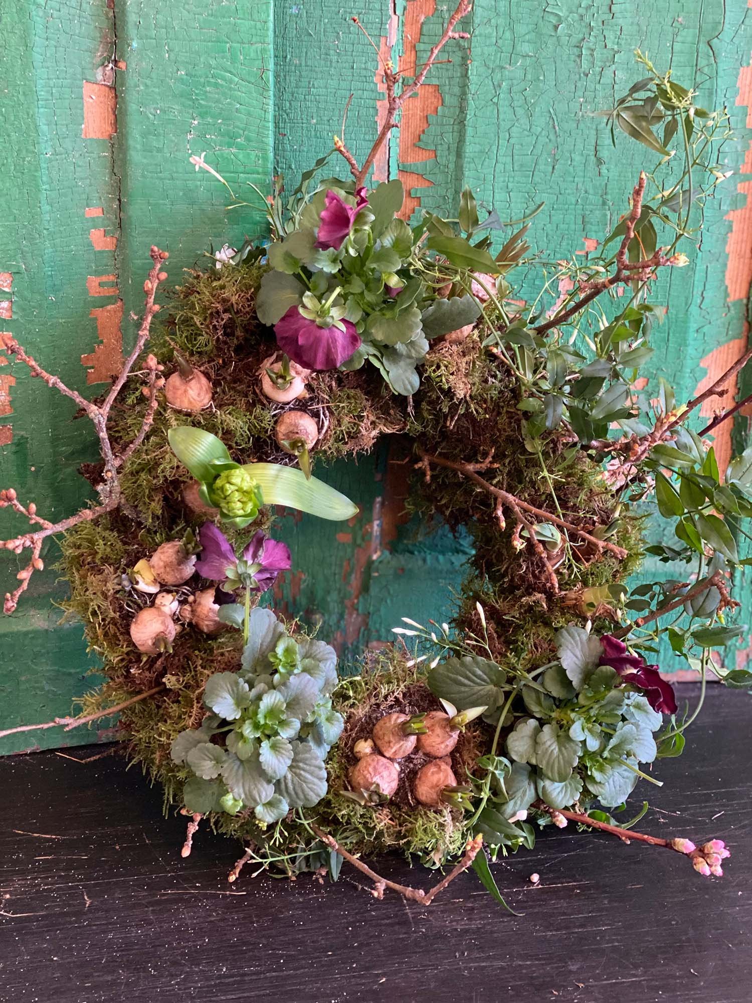 A spring bulb living wreath in front of a bright green door