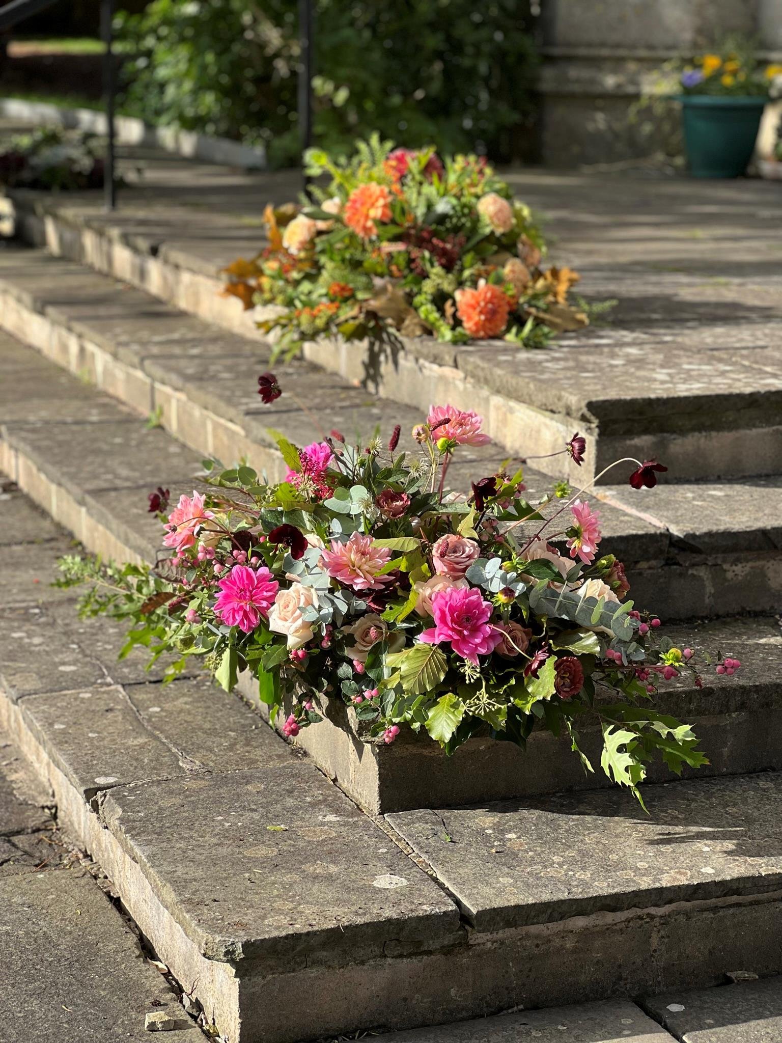 Two natural funeral flower arrangements placed on church steps