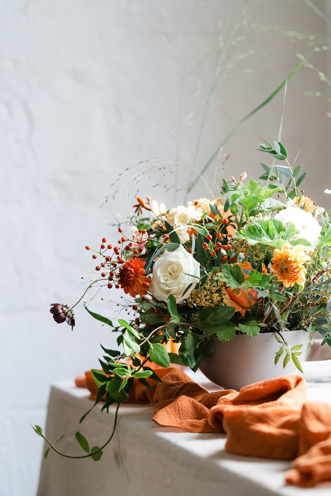 Low flower arrangement placed on table with burnt orange linen