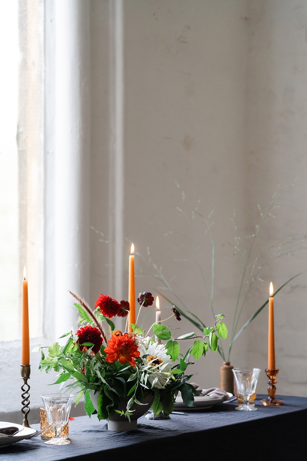 Flowery table centrepiece set on a dark clothed table with candles