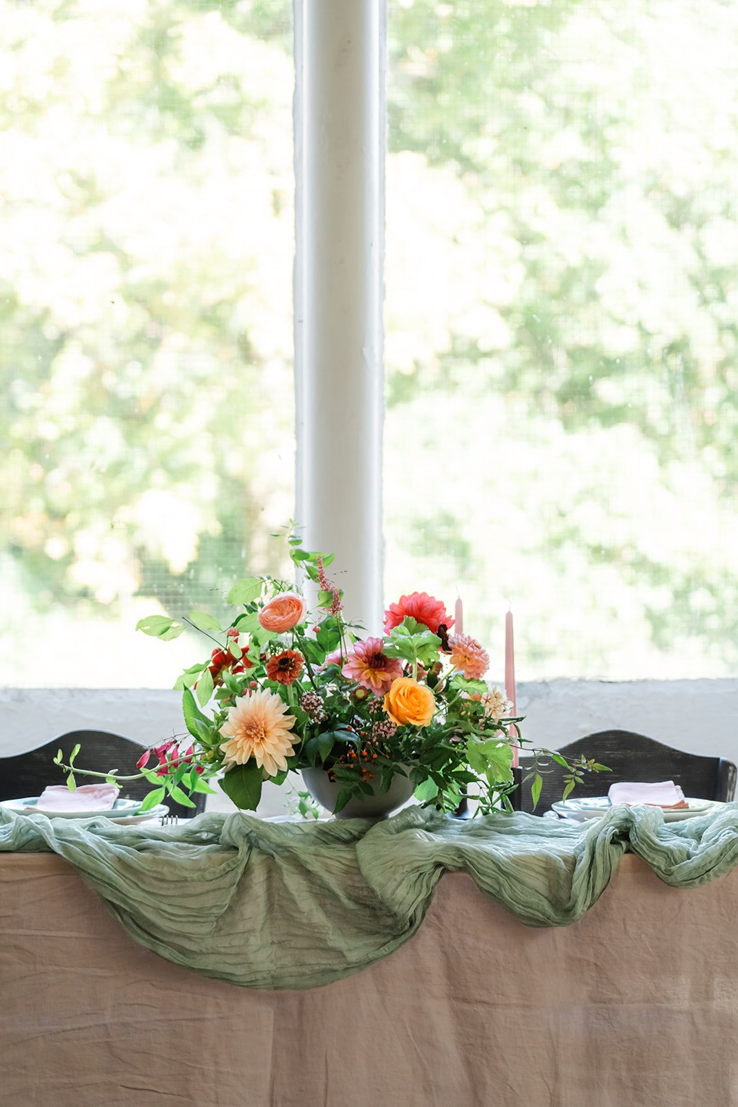 Table dressed with green linen and a foam free flower arrangement
