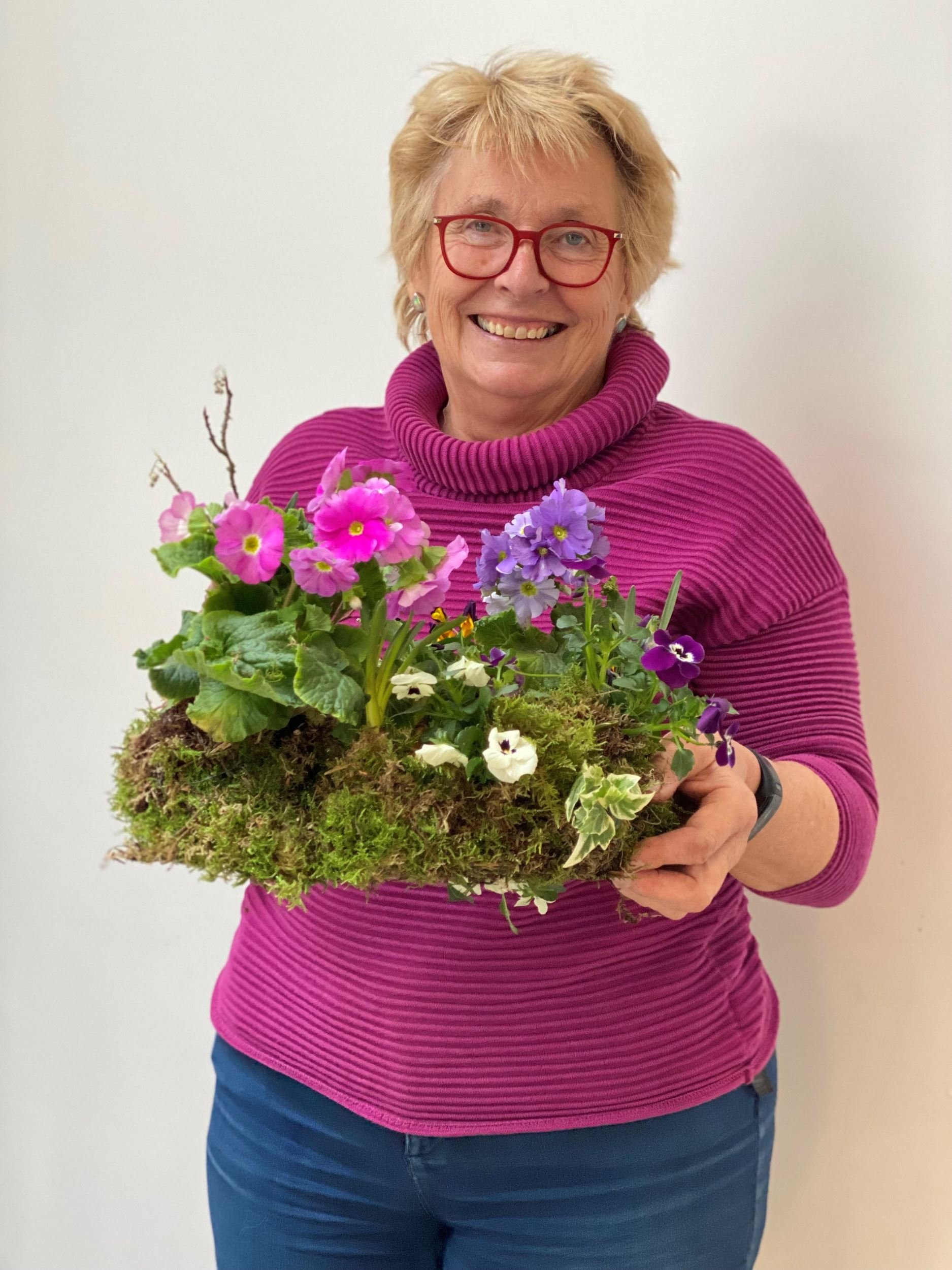 Lady in purple jumper holding a spring bulb living wreath at The Bath Flower School 
