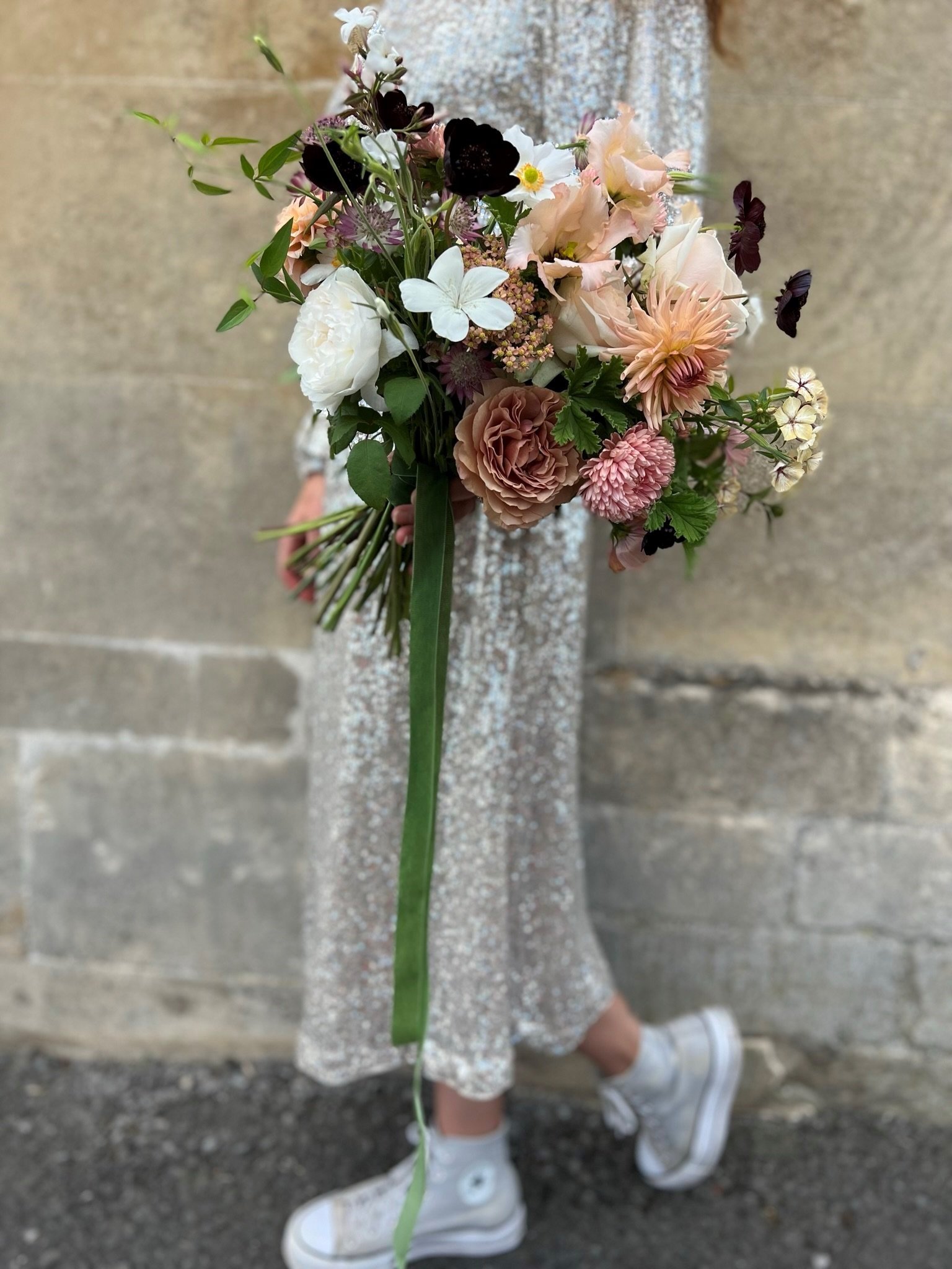 Student wearing sequin wedding dress, converse trainers holding a autumnal bridal bouquet