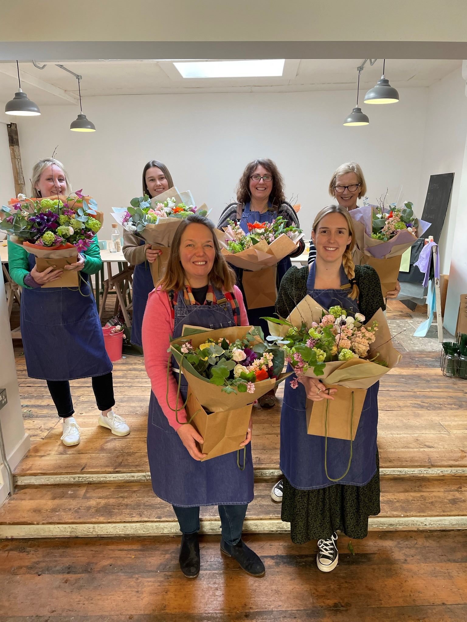 Students holding their beautiful spring hand tied bouquets in The Bath Flower School room