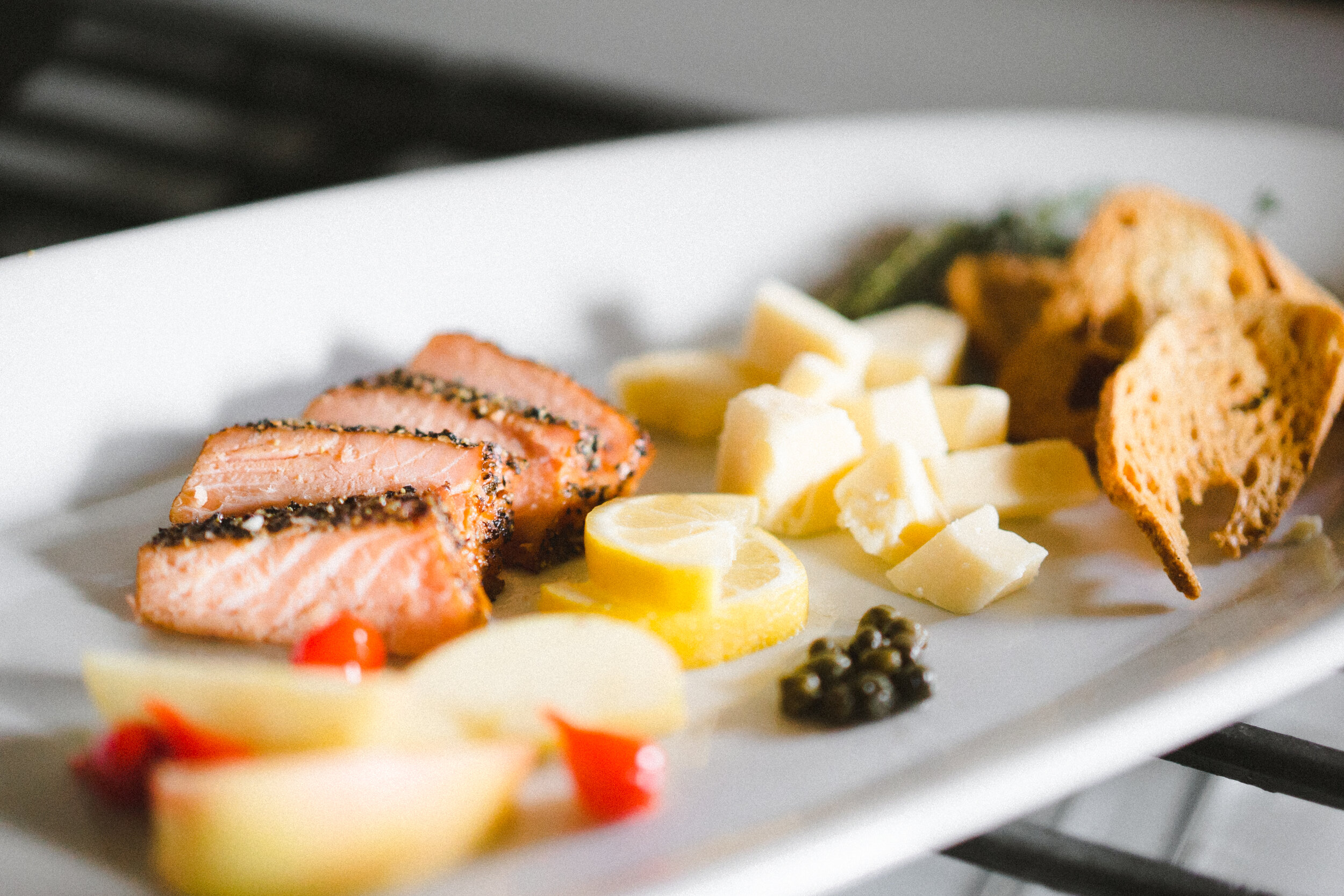 Artistic Shot of Smoked Black Pepper and Coriander Salmon on a Platter with Various Accompaniments