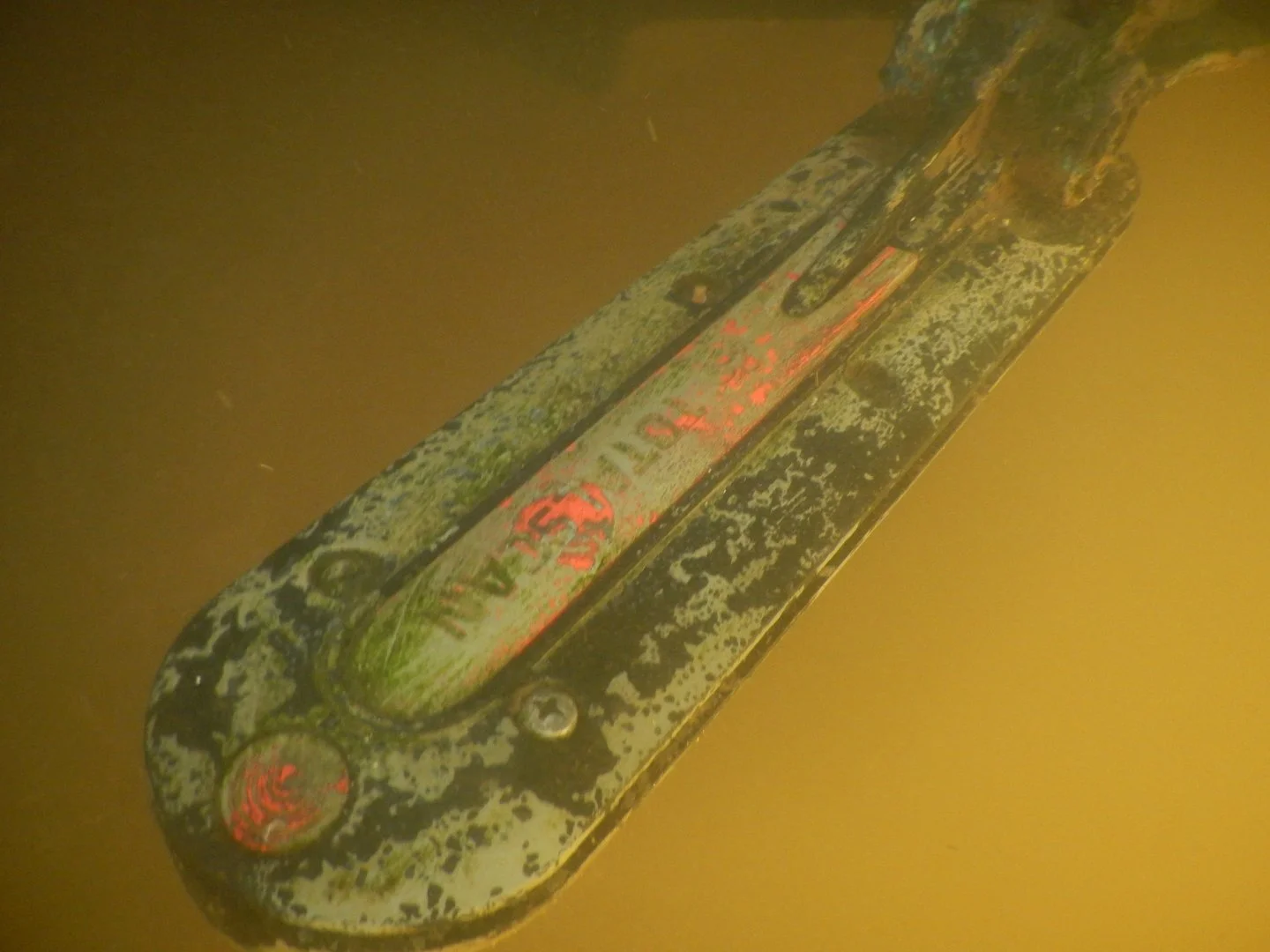 Clean boat transducer underwater after removal of marine growth buildup.