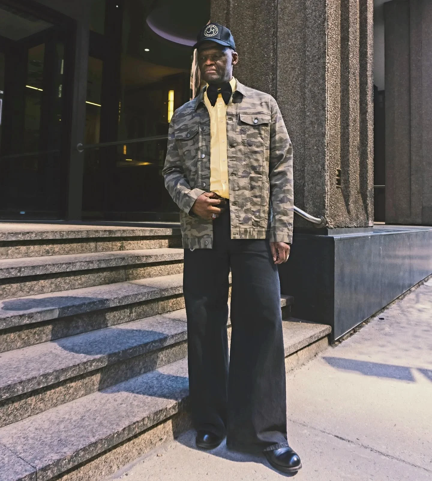 Trucker hat, yellow shirt, black jeans 👖  black bow tie &amp; camo jacket by JMC