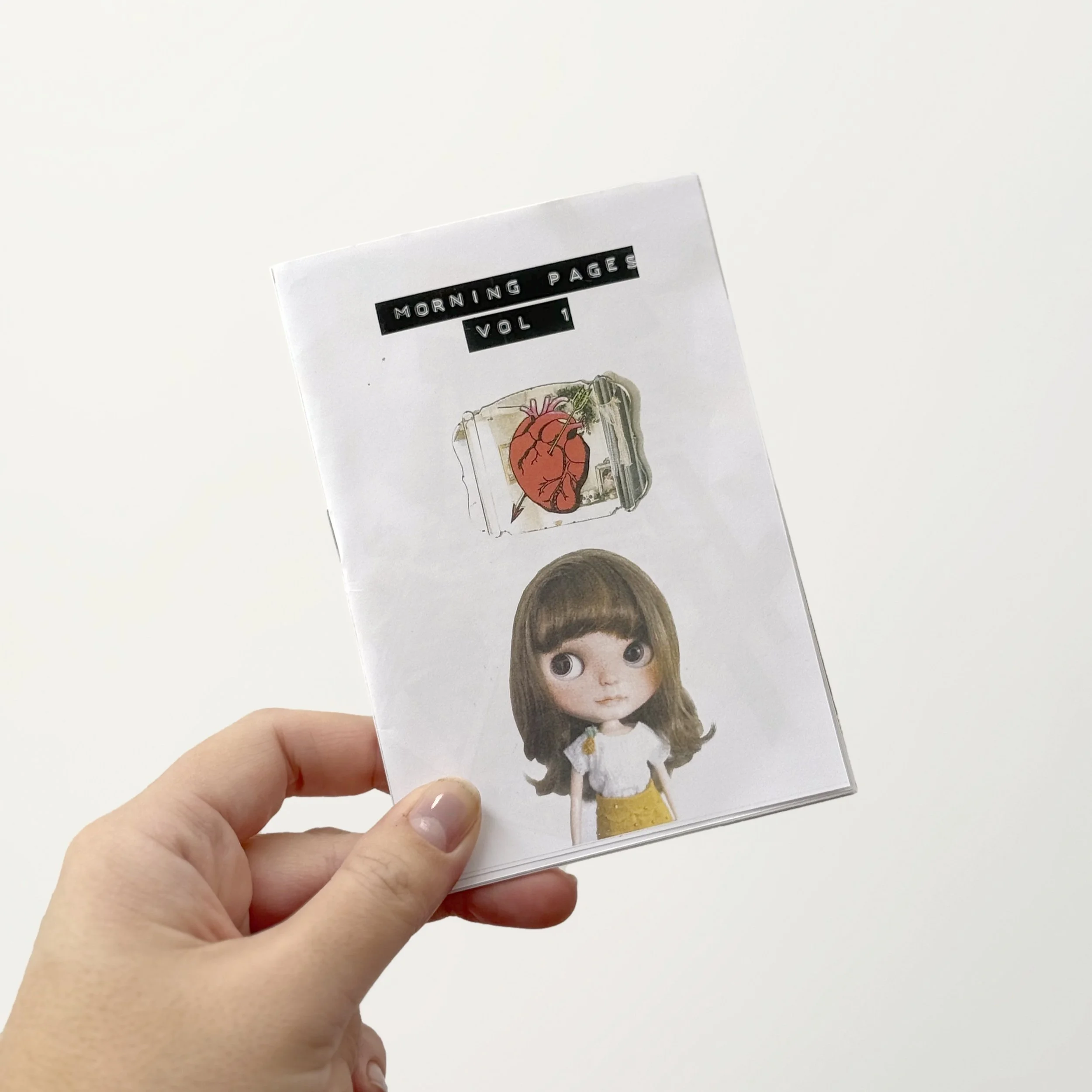 Hand holding the Morning Pages Vol. 1 indie art zine by NZ artist Nicole Keane, showing the collaged Blythe doll cover with embossed tape title